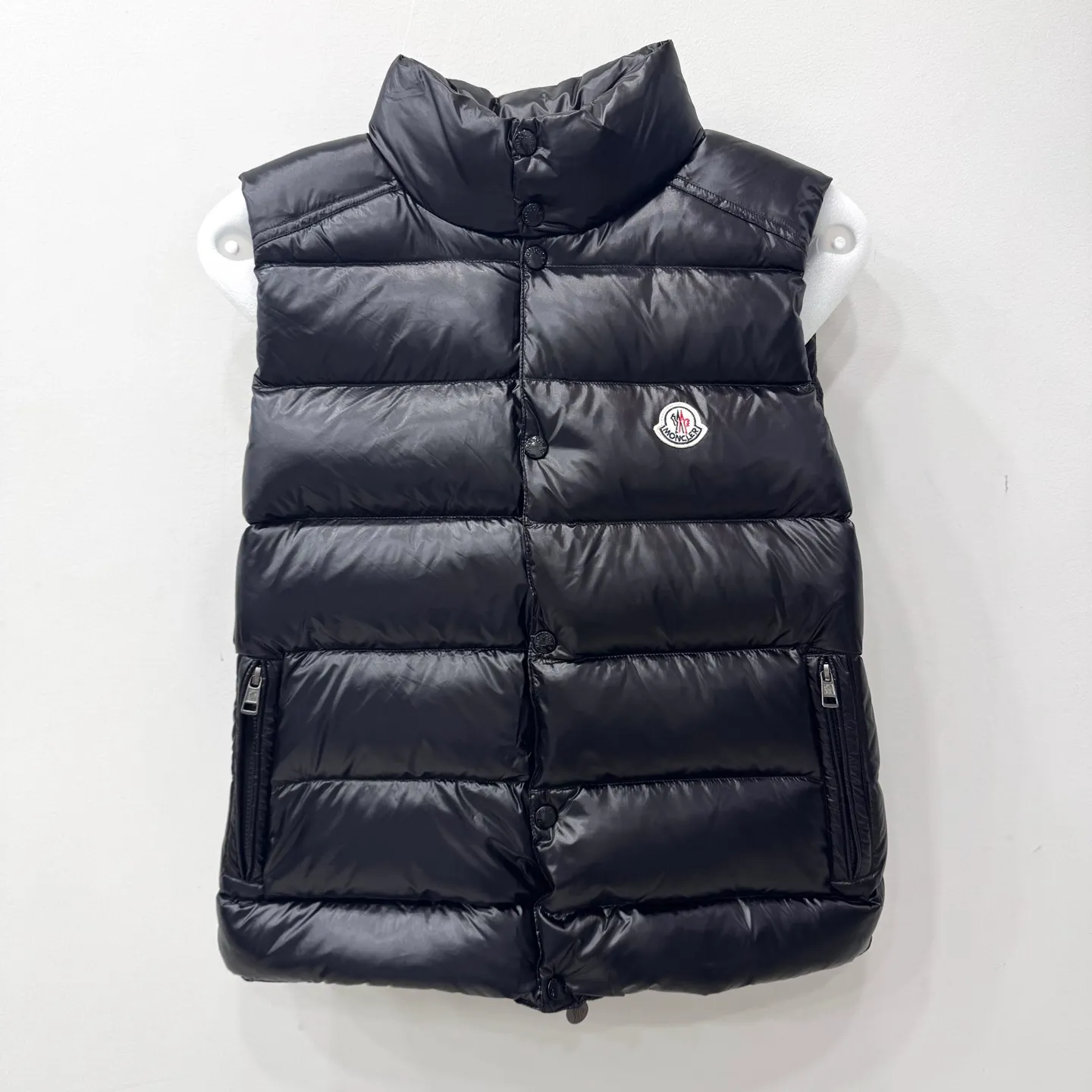 P560 Tibb men's down vest] Tibb men's down vest is a classic Moncler design item made of nylon laqué fabric.     The Tibb men's down vest is a classic Moncler item, inspired by the iconic archival silhouette of the 1980s. Made from lightweight nylon laqué functional fabric, it's perfect for changing seasons.  •Made of nylon laqué •Nylon laqué lining •Down filled •Snap-stud collar •Zip closure •Zip pockets •Fabric: 100% nylon; •Lining: 100% nylon; •Filling: goose down •Down content: 90%; except trim; •Size: 12345 Maximum wash temperature 30°C - Gentle wash; Do not bleach; Do not tumble dry; Ironing maximum temperature 110°C - without steam; Do not dry clean; Professional wet cleaning - Gentle wash; Lay flat to dry in shade; Wash separately; Recommend washing and ironing inside out