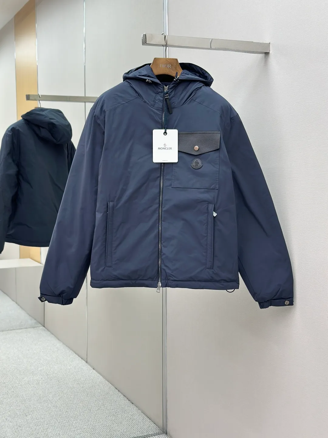 P890 MONCLER hooded jacket-style down jacket is made of 100% polyester fiber. After microfiberization treatment, the individual fibers become extremely fine, which greatly increases the fiber surface area, making the fabric soft and smooth, and the touch is close to natural fibers. The high-density textile method makes the structure tight, thus giving it a certain degree of wrinkle resistance, windproof warmth and wear resistance.  Lining selection: High-density lining fabric made of ultra-fine denier, 0.08mm thickness to avoid increasing the overall weight and making it smooth to wear. The high-density woven structure forms a wind resistance layer to protect the thermal efficiency of the thermal layer from loss. It can also withstand the expansion pressure of down and prevent deformation and damage after long-term use.  High-quality filling: 90 white duck down is selected, with a weight of 200g, ensuring excellent thermal insulation performance. After strict screening and treatment, the velvet is not easy to be drilled, ensuring durability. Details: The leather flap pocket on the chest is matched with a pebbled leather flap + matte metal buckle. It is low-key and exudes nobility. The hidden adjustment rope gives a sense of sophistication when you raise your hand. The "ID card" is directly embedded on the black satin inner patch pocket! Silver snaps + red, white and blue webbing, low-key yet exuding a sense of luxury, both visually and tactilely smooth.  Accessories: one-to-one customized buttons, one-to-one customized hem drawstring buckle, one-to-one customized phoenix eyes, one-to-one customized zipper pendant SIZE: 1 2 3 4
