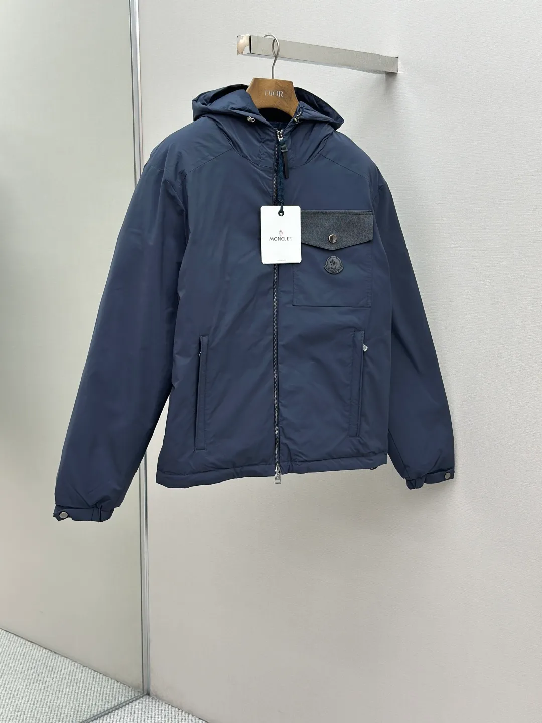 P890 MONCLER hooded jacket-style down jacket is made of 100% polyester fiber. After microfiberization treatment, the individual fibers become extremely fine, which greatly increases the fiber surface area, making the fabric soft and smooth, and the touch is close to natural fibers. The high-density textile method makes the structure tight, thus giving it a certain degree of wrinkle resistance, windproof warmth and wear resistance.  Lining selection: High-density lining fabric made of ultra-fine denier, 0.08mm thickness to avoid increasing the overall weight and making it smooth to wear. The high-density woven structure forms a wind resistance layer to protect the thermal efficiency of the thermal layer from loss. It can also withstand the expansion pressure of down and prevent deformation and damage after long-term use.  High-quality filling: 90 white duck down is selected, with a weight of 200g, ensuring excellent thermal insulation performance. After strict screening and treatment, the velvet is not easy to be drilled, ensuring durability. Details: The leather flap pocket on the chest is matched with a pebbled leather flap + matte metal buckle. It is low-key and exudes nobility. The hidden adjustment rope gives a sense of sophistication when you raise your hand. The "ID card" is directly embedded on the black satin inner patch pocket! Silver snaps + red, white and blue webbing, low-key yet exuding a sense of luxury, both visually and tactilely smooth.  Accessories: one-to-one customized buttons, one-to-one customized hem drawstring buckle, one-to-one customized phoenix eyes, one-to-one customized zipper pendant SIZE: 1 2 3 4