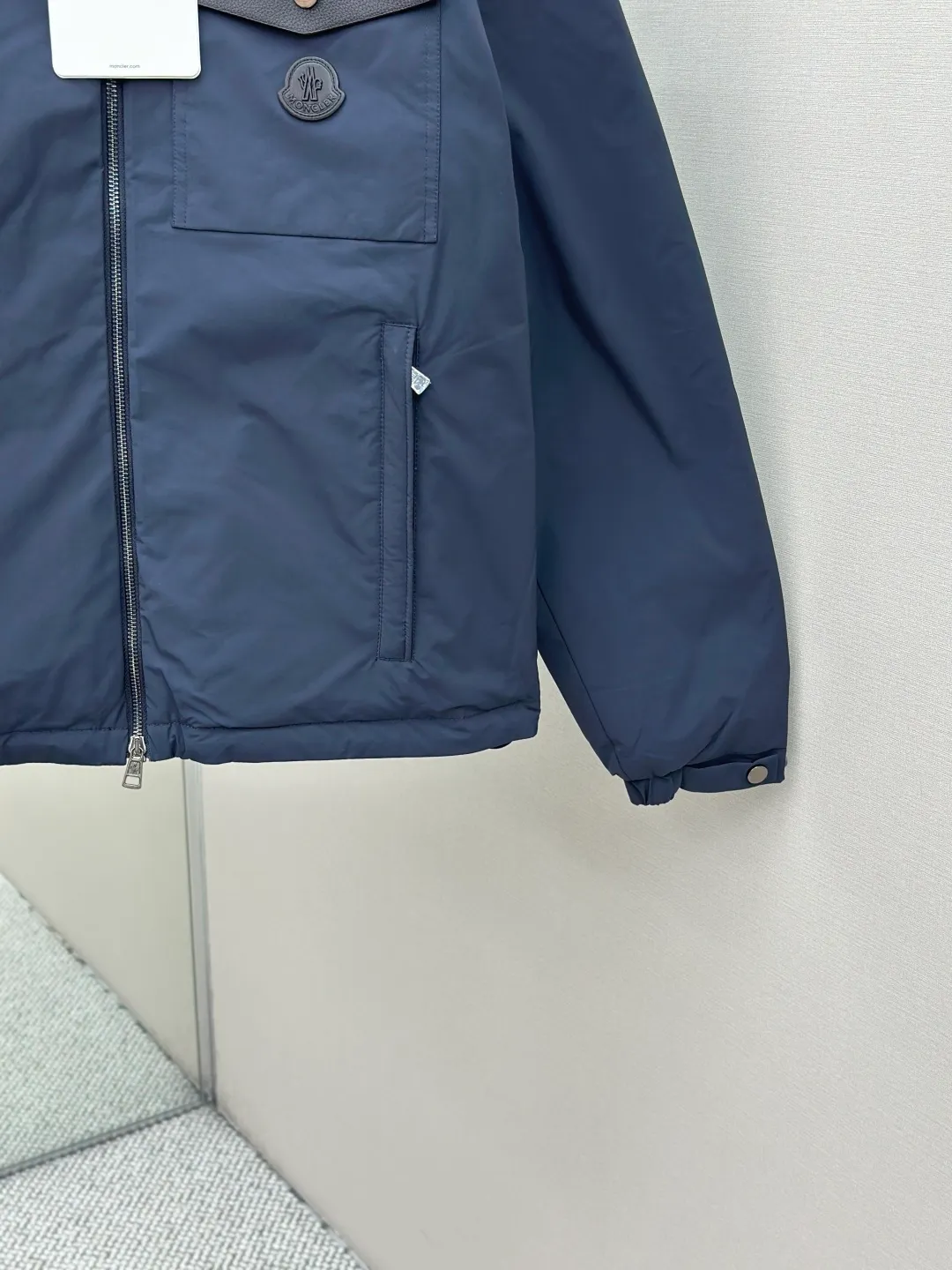 P890 MONCLER hooded jacket-style down jacket is made of 100% polyester fiber. After microfiberization treatment, the individual fibers become extremely fine, which greatly increases the fiber surface area, making the fabric soft and smooth, and the touch is close to natural fibers. The high-density textile method makes the structure tight, thus giving it a certain degree of wrinkle resistance, windproof warmth and wear resistance.  Lining selection: High-density lining fabric made of ultra-fine denier, 0.08mm thickness to avoid increasing the overall weight and making it smooth to wear. The high-density woven structure forms a wind resistance layer to protect the thermal efficiency of the thermal layer from loss. It can also withstand the expansion pressure of down and prevent deformation and damage after long-term use.  High-quality filling: 90 white duck down is selected, with a weight of 200g, ensuring excellent thermal insulation performance. After strict screening and treatment, the velvet is not easy to be drilled, ensuring durability. Details: The leather flap pocket on the chest is matched with a pebbled leather flap + matte metal buckle. It is low-key and exudes nobility. The hidden adjustment rope gives a sense of sophistication when you raise your hand. The "ID card" is directly embedded on the black satin inner patch pocket! Silver snaps + red, white and blue webbing, low-key yet exuding a sense of luxury, both visually and tactilely smooth.  Accessories: one-to-one customized buttons, one-to-one customized hem drawstring buckle, one-to-one customized phoenix eyes, one-to-one customized zipper pendant SIZE: 1 2 3 4