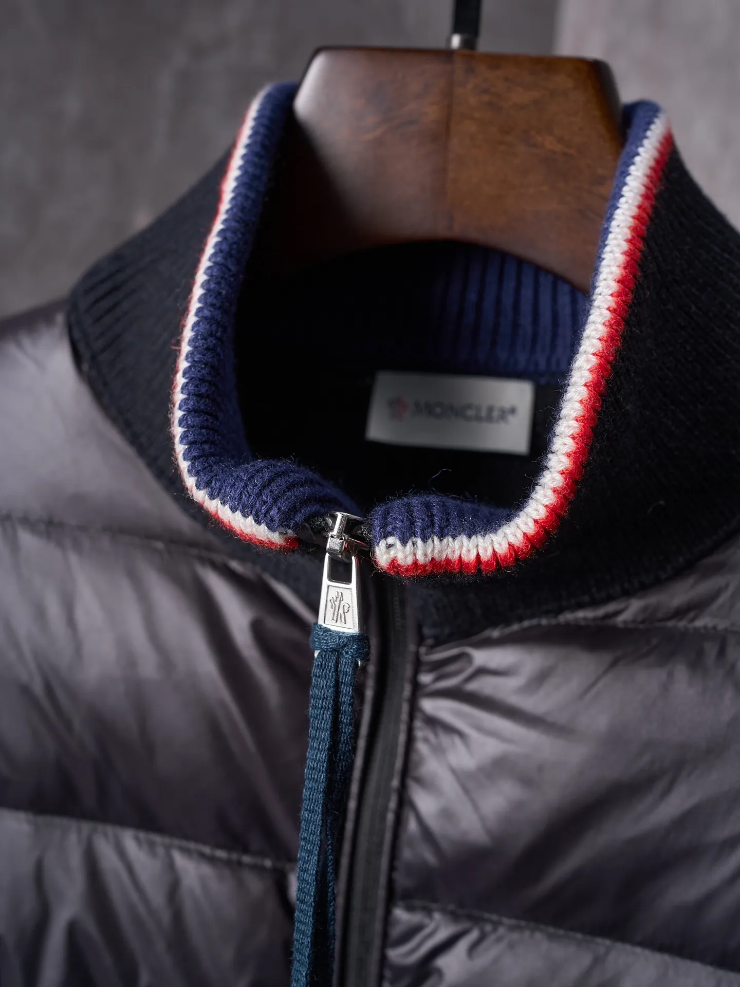 P820 ​​Actual hanging auction] MONCLER/Mask quilted wool splicing zipper three-color trim stand-up collar down jacket [Ready stock] 1 2 3 4 high-quality white duck down filling, with a filling capacity of 130g, excellent warmth retention effect.  The front body fabric is made of 100% polyester fiber with high-density weaving. The thickness of 0.08mm avoids increasing the overall weight and is smooth. The high-density weaving structure forms a wind resistance layer to protect the thermal efficiency of the thermal layer from loss. It can withstand the expansion pressure of down and prevent deformation and damage after long-term use.  7-needle medium-thick knitted structure: Use thicker yarns to knit woolen fabrics with obvious thickness and weight. The texture is clearly visible and has a rough, retro texture. It has a good skeleton feel, is relatively stiff, and can maintain the silhouette of clothing for a long time. It also provides more layers of still air to lock in heat.  The three-color trim at the collar draws traditional inspiration and becomes the finishing touch. Smooth pocket zipper closure enhances practicality and aesthetics.