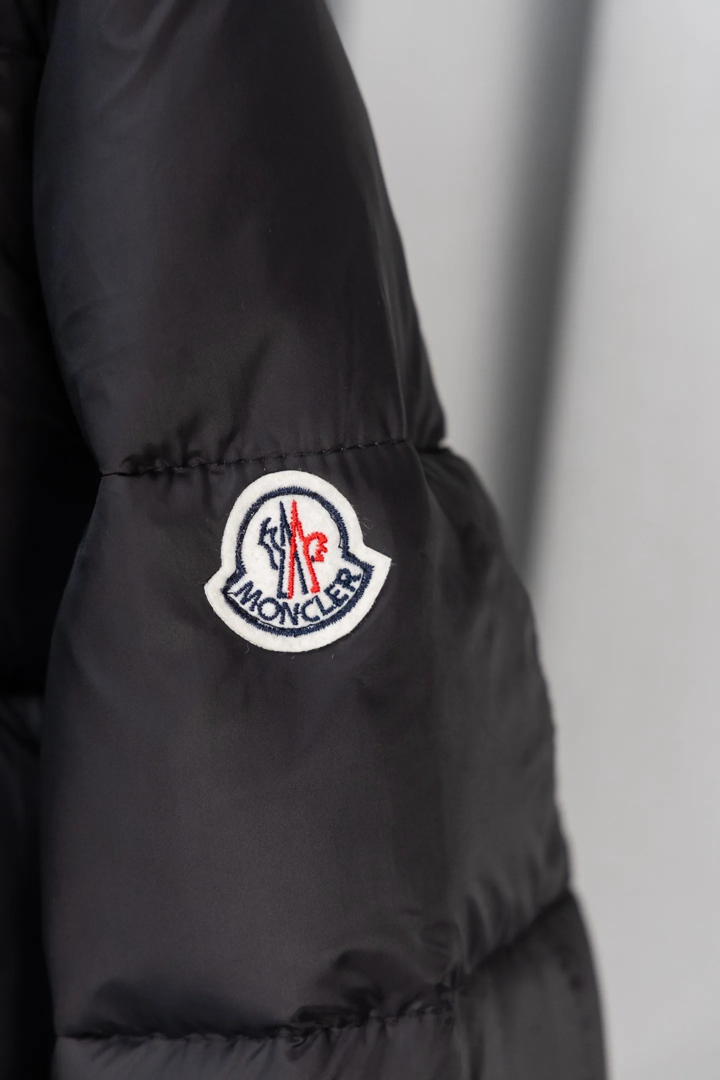 P570 model number: S038 Moncler Parana series is a classic item of the brand that combines retro style with modern functionality. It continues Moncler’s iconic felt badges on sleeves and arms, low-key highlighting the brand identity, and is the core embodiment of luxury recognition. The design is inspired by the "Paninaro culture" of the 1980s, paying tribute to classics with glossy materials and retro silhouettes, while injecting modern street trend genes to achieve a collision of retro and avant-garde styles. Fabric: Made of the brand's exclusive high-gloss lacquered nylon (Nylon laqué), which has anti-fouling and anti-static properties. The glossy texture is visually impactful and can effectively reflect light, making the outfit more eye-catching. It has strong warmth retention while maintaining a light body feel, achieving a "warm and burden-free" wearing experience.  Detachable hood: The hood is designed with khaki color splicing to form a visual contrast with the black main body; it can be flexibly detached according to weather and styling needs, adapting to a variety of scenes.  Double closure system: The front placket adopts a "zipper + snap button" combination, which improves wind resistance and warmth while enhancing the layering of the style. Detailed configuration: Zipper pockets on both sides are practical and decorative, elastic cuffs can lock in temperature, and the drawstring design on the hem can adjust the silhouette according to the body shape, reflecting humanized functionality at every turn. The loose version of the same style for men and women is highly tolerant to the body and is a high-quality choice for couples. It can easily realize the style expression of "high-end couple wear" and is suitable for daily commuting, outdoor leisure and other diverse scenes. Size: S-XL