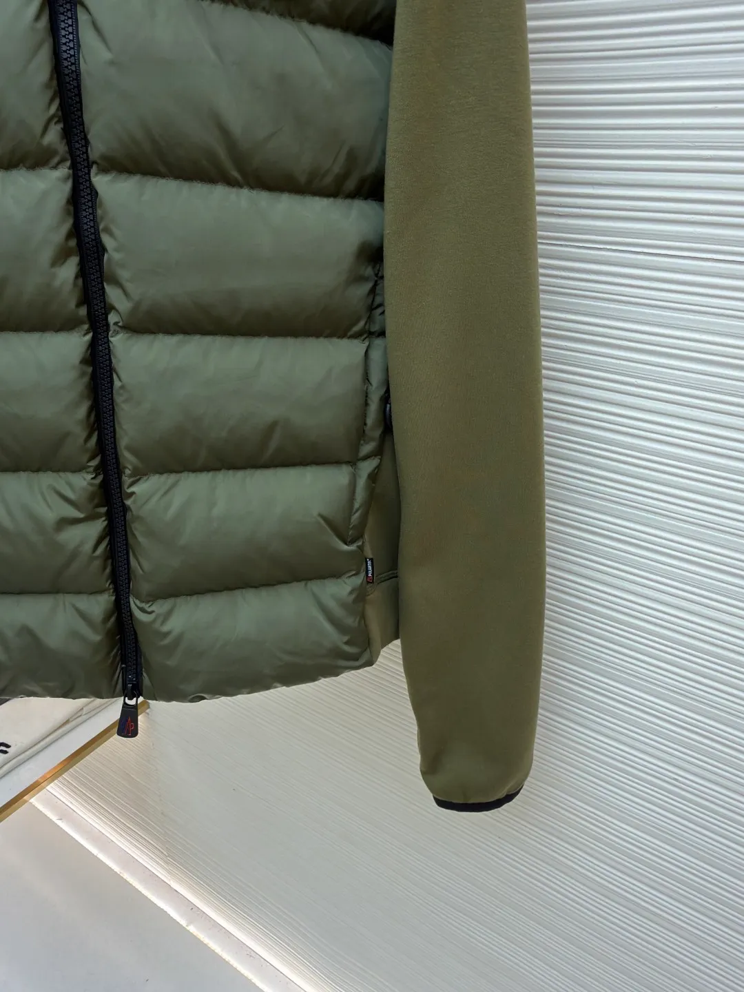P810 Moncler logo woven splicing down jacket ●Item number: 1682128-C65 ●Material: white duck down fabric ●Technology: mechanical down filling ●Color: green ●Version: fitted version ●Weight: about 700 grams ●Size: S-M-L-XL ●Description: Customized matte lattice air shield down and 300D high-density calendered coating Use the new national standard 90 white duck down (welcome to test) Full flushing capacity Full of warmth, light and fluffy. With the dark green of the overlapping mountains as the background color, all things accumulate energy and create their own scenery in silence. The Monlcer triangle logo is embellished on the chest. The power aesthetics of the minimalist logo. The concentrated down filling in the front area creates dynamic insulation for the core heat dissipation zone of the human body. The hooded down is a moving warm flow barrier for the head and neck, forming a thermal energy circulation system with the front panel. The elastic woven sleeves provide freedom of movement with a sense of compression, forming a relaxed and warm philosophy, truly advanced. It is a mechanical down filling that allows function to become a footnote of style. Priority is given to making inner liner paper patterns to determine the down filling area and the gram weight of down per square meter according to the original three-dimensional effect, thereby calculating the filling amount of each cut piece. The computer down filling machine uses a digital weighing unit to achieve stable measurement. 3D three-dimensional quilting technology uses the programming system of the CNC quilting machine to accurately separate the down in different areas to ensure that the filling is evenly fixed after sewing. To avoid agglomeration or shifting, the template machine lines the lines. The line line process of the computer template machine shows extremely high neatness and smoothness. The craftsman accurately controls the size during the operation to ensure that each line meets the design requirements. The lines of the entire template are smooth and unified. Neat and beautiful, triple seam five-thread dense stitching process The triple structure of main seam overlocking + diagonal reinforcement + raw edge wrapping forms a three-dimensional protective net at the edge of the fabric to avoid stitch breakage. The overall wiring is straight and delicate, the fabric is comfortable and soft, and the color is consistent without color difference. It can be matched with the same style to create a fashionable look and control various occasions. Customized accessories, complete with three standards, same style for men and women!