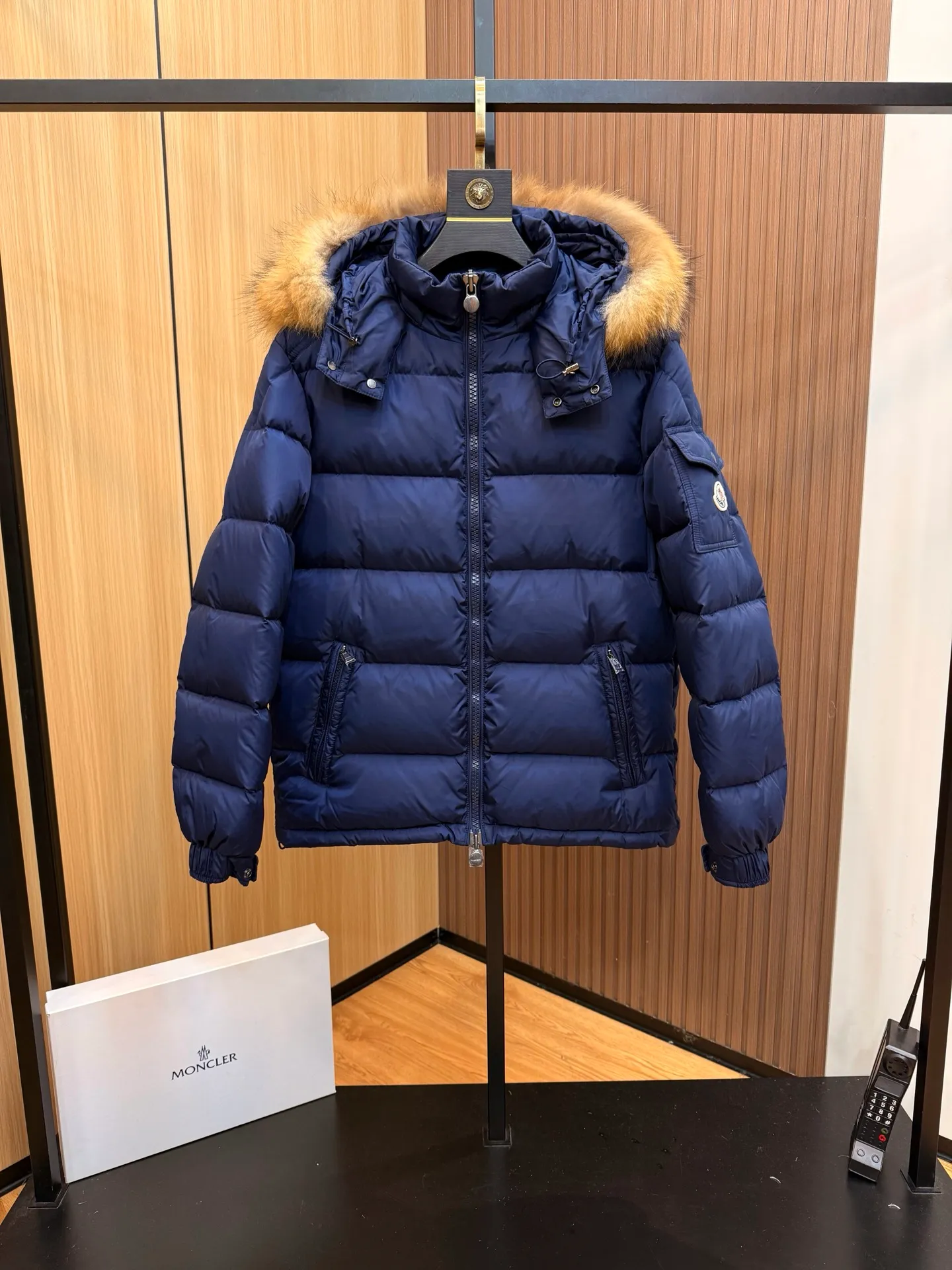 P1000 Moncler Mayaf short men's down jacket jacket. The hood is removable. The fur collar is removable. Based on Maya, a removable fur collar is added. The Mayaf men's hooded down jacket is made of functional nylon fabric, and the hood is equipped with removable synthetic material trim.  The Mayaf short down jacket is a reinterpretation of the classic Moncler Maya style in an instantly recognizable silhouette, with a removable hood and adjustable hem. Made from functional fabric with removable synthetic trim on the hood. The sleeves are embellished with classic patch pockets, reflecting the brand's signature style. Details •Made from functional fabric •Technical fabric lining •Down-filled •Push-stud collar •Detachable hood with removable synthetic trim •Zip closure •Zip pockets •Patch pockets with press-stud •Adjustable elastic cuffs •Adjustable drawstring hem