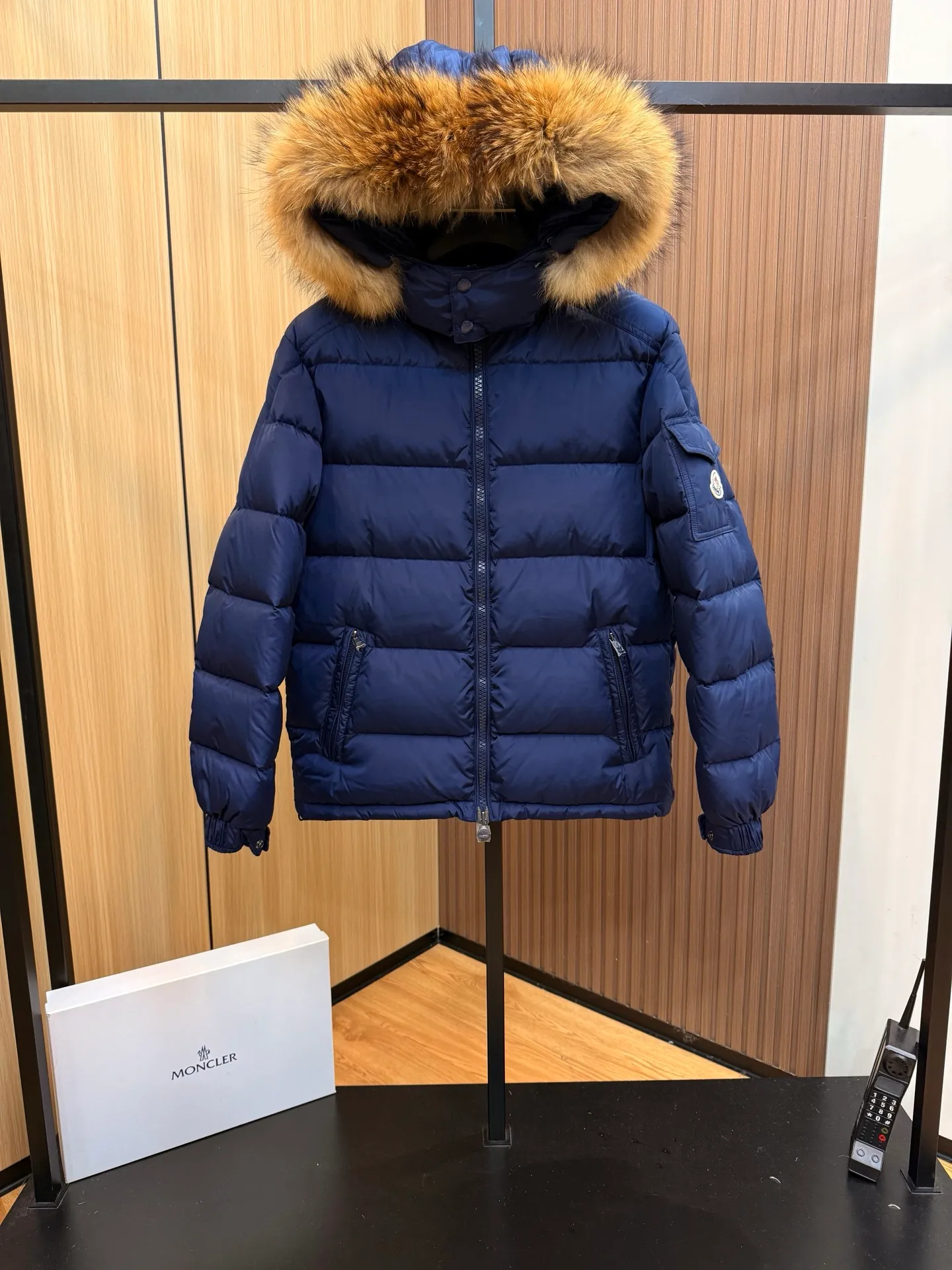P1000 Moncler Mayaf short men's down jacket jacket. The hood is removable. The fur collar is removable. Based on Maya, a removable fur collar is added. The Mayaf men's hooded down jacket is made of functional nylon fabric, and the hood is equipped with removable synthetic material trim.  The Mayaf short down jacket is a reinterpretation of the classic Moncler Maya style in an instantly recognizable silhouette, with a removable hood and adjustable hem. Made from functional fabric with removable synthetic trim on the hood. The sleeves are embellished with classic patch pockets, reflecting the brand's signature style. Details •Made from functional fabric •Technical fabric lining •Down-filled •Push-stud collar •Detachable hood with removable synthetic trim •Zip closure •Zip pockets •Patch pockets with press-stud •Adjustable elastic cuffs •Adjustable drawstring hem
