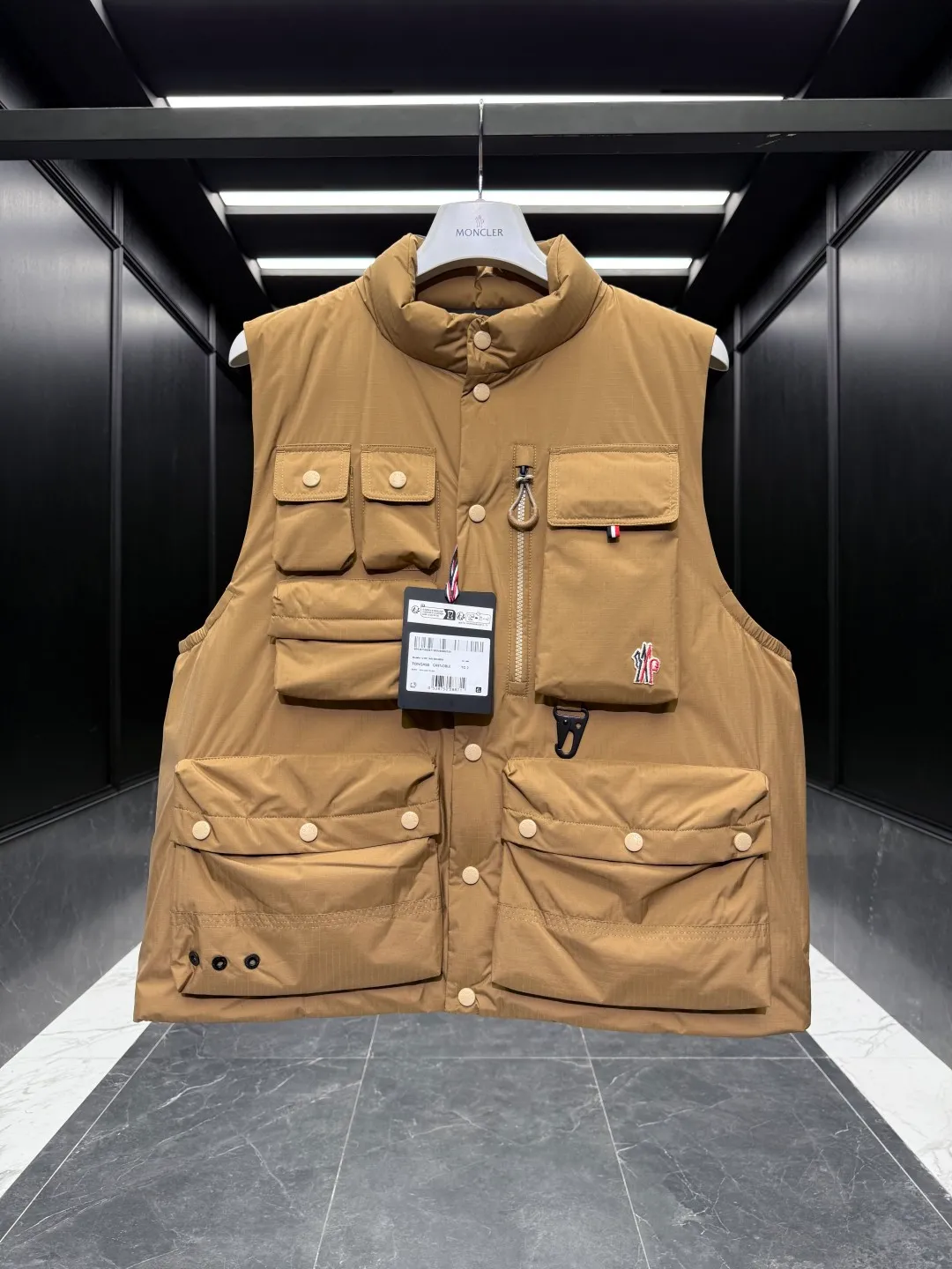 P860 Premium Down⬆️Moncler Grenoble Tongass Down Outdoor Vest. High-end Black Label Series. Original replacement fabric. Premium gooseneck filling. 🎁 Comes standard with a full set of counter gift box packaging. Upgraded original magnetic gift box. The Tongass Down Vest provides protection without being heavy, and is specially designed for outdoor activities in mild weather.  The Tongass down vest is the result of research into lightweight performance outerwear. Functional fabric is tight and durable without adding extra weight. Features a large utility pocket and carabiner clip to reduce the amount of luggage you carry. Details •Designed for outdoor activities •Made from tight fabric •Polyester lining •Down filling •Snap button closure •Utility pockets with snap, zip and Velcro closure •Drawstring hem •Front carabiner •Reflective details Size: 1-5 Cream/Light Brown/Black D00780