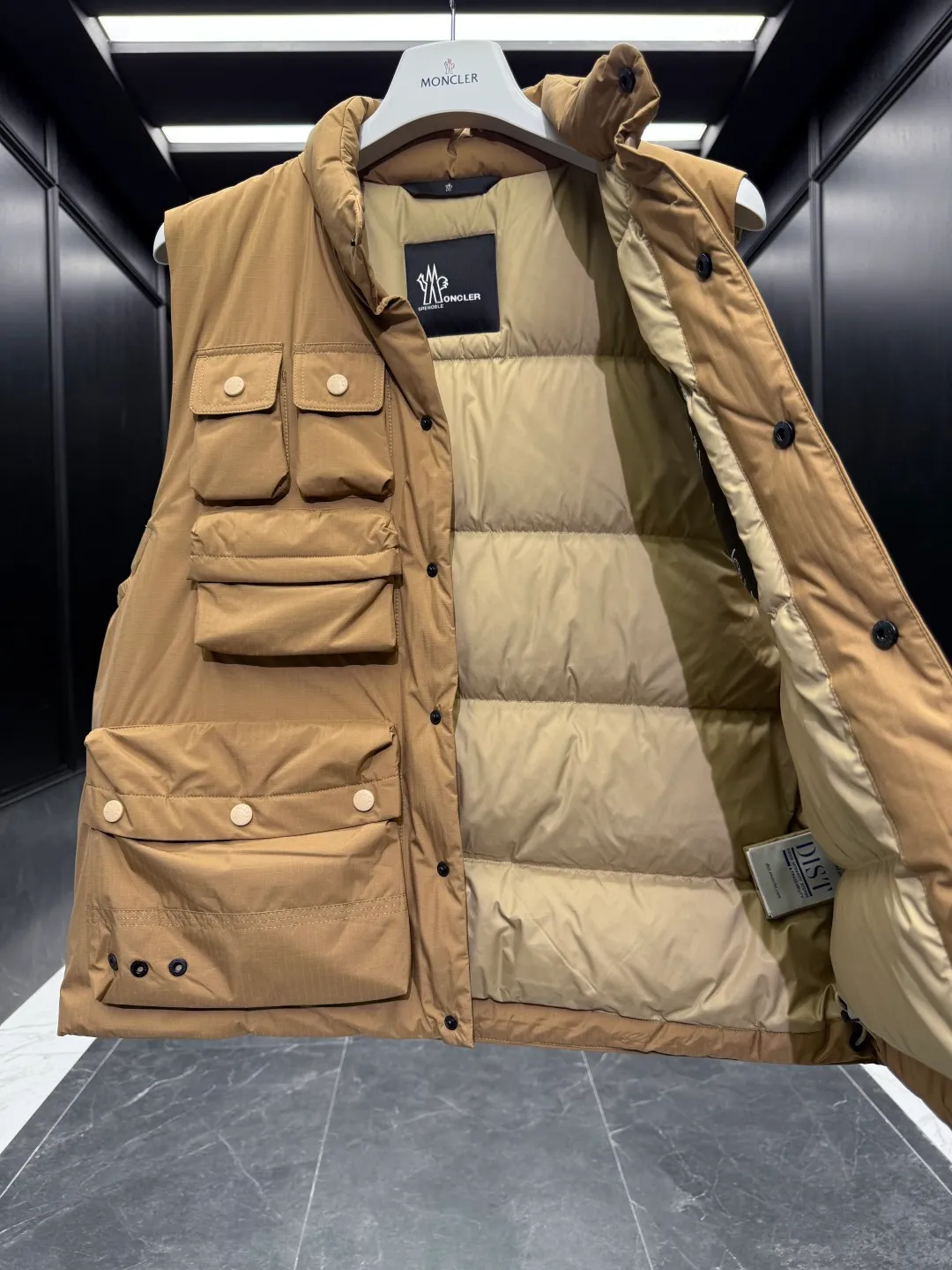 P860 Premium Down⬆️Moncler Grenoble Tongass Down Outdoor Vest. High-end Black Label Series. Original replacement fabric. Premium gooseneck filling. 🎁 Comes standard with a full set of counter gift box packaging. Upgraded original magnetic gift box. The Tongass Down Vest provides protection without being heavy, and is specially designed for outdoor activities in mild weather.  The Tongass down vest is the result of research into lightweight performance outerwear. Functional fabric is tight and durable without adding extra weight. Features a large utility pocket and carabiner clip to reduce the amount of luggage you carry. Details •Designed for outdoor activities •Made from tight fabric •Polyester lining •Down filling •Snap button closure •Utility pockets with snap, zip and Velcro closure •Drawstring hem •Front carabiner •Reflective details Size: 1-5 Cream/Light Brown/Black D00780