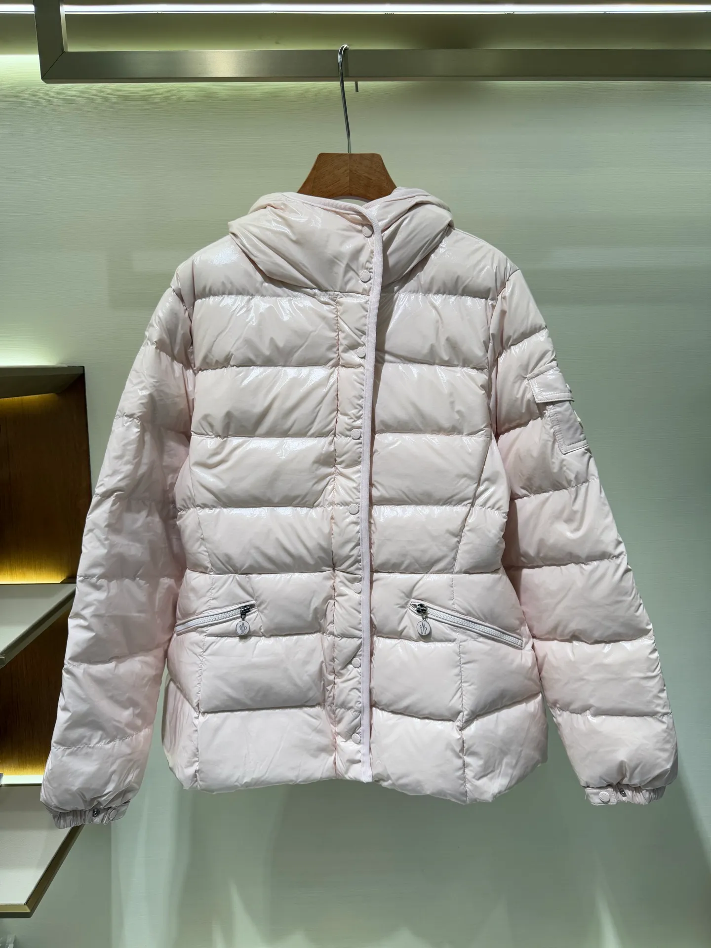 P1140 Moncler Barante series short waisted down jacket. The Barante down jacket is made of glossy nylon fabric and is inspired by the 1970s. The short version features a nipped-in waist and an A-line silhouette, highlighting a feminine style. An adjustable hood and signature logo patch add finishing touches.  Fabric: Made of nylon laque fabric, Nylon laque lining, filled with down (90 white goose down) Craftsmanship: Adjustable hood, zipper and snap closure, zipper pocket Adjustable cuffs (supports NFC function Color: black pink off-white Size: 0 1 2 3 4446080