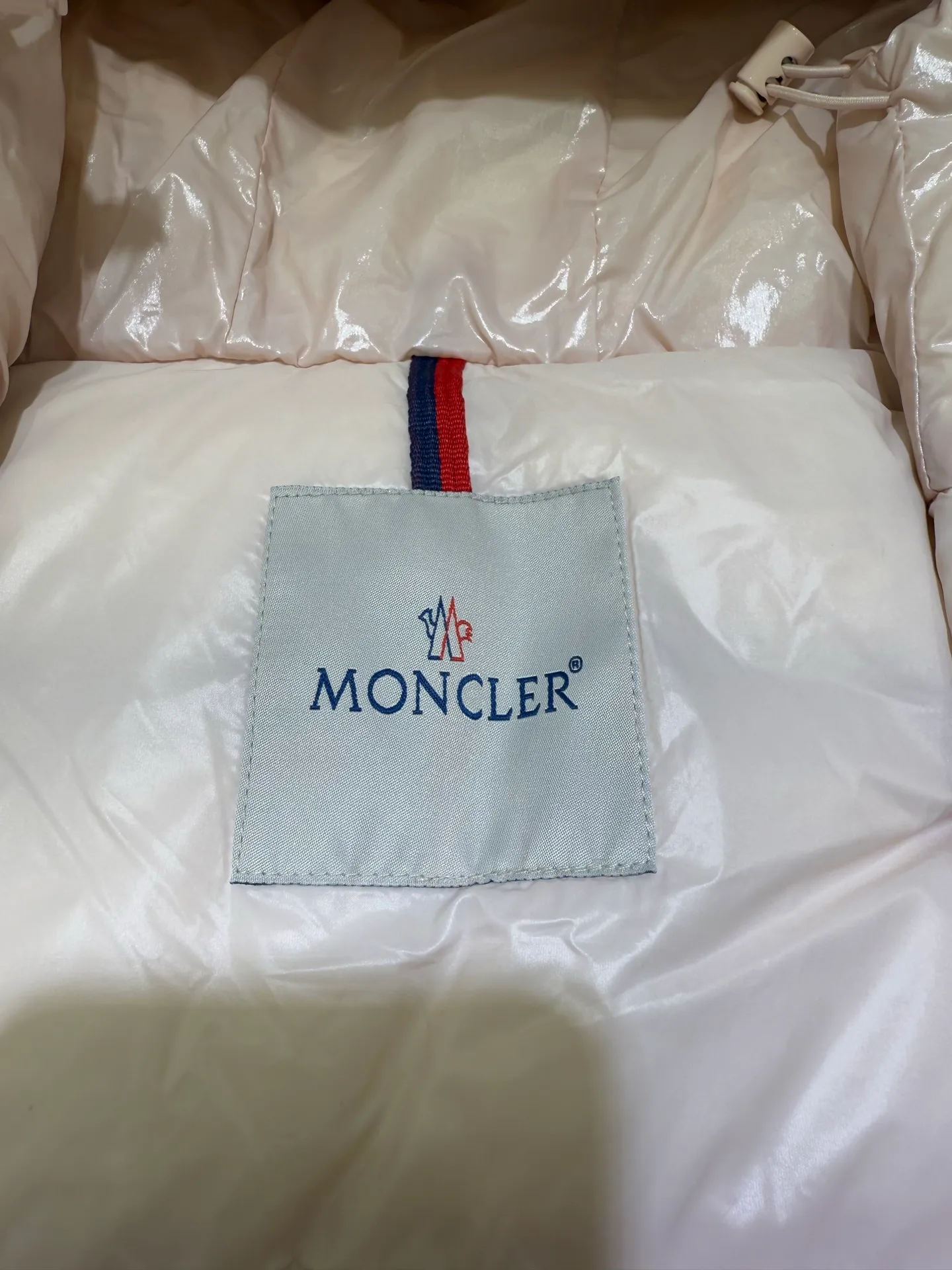P1140 Moncler Barante series short waisted down jacket. The Barante down jacket is made of glossy nylon fabric and is inspired by the 1970s. The short version features a nipped-in waist and an A-line silhouette, highlighting a feminine style. An adjustable hood and signature logo patch add finishing touches.  Fabric: Made of nylon laque fabric, Nylon laque lining, filled with down (90 white goose down) Craftsmanship: Adjustable hood, zipper and snap closure, zipper pocket Adjustable cuffs (supports NFC function Color: black pink off-white Size: 0 1 2 3 4446080