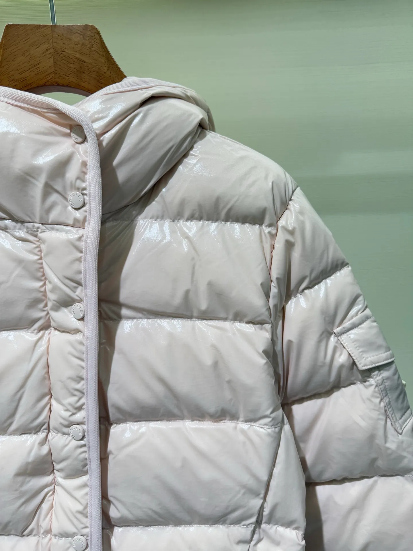 P1140 Moncler Barante series short waisted down jacket. The Barante down jacket is made of glossy nylon fabric and is inspired by the 1970s. The short version features a nipped-in waist and an A-line silhouette, highlighting a feminine style. An adjustable hood and signature logo patch add finishing touches.  Fabric: Made of nylon laque fabric, Nylon laque lining, filled with down (90 white goose down) Craftsmanship: Adjustable hood, zipper and snap closure, zipper pocket Adjustable cuffs (supports NFC function Color: black pink off-white Size: 0 1 2 3 4446080