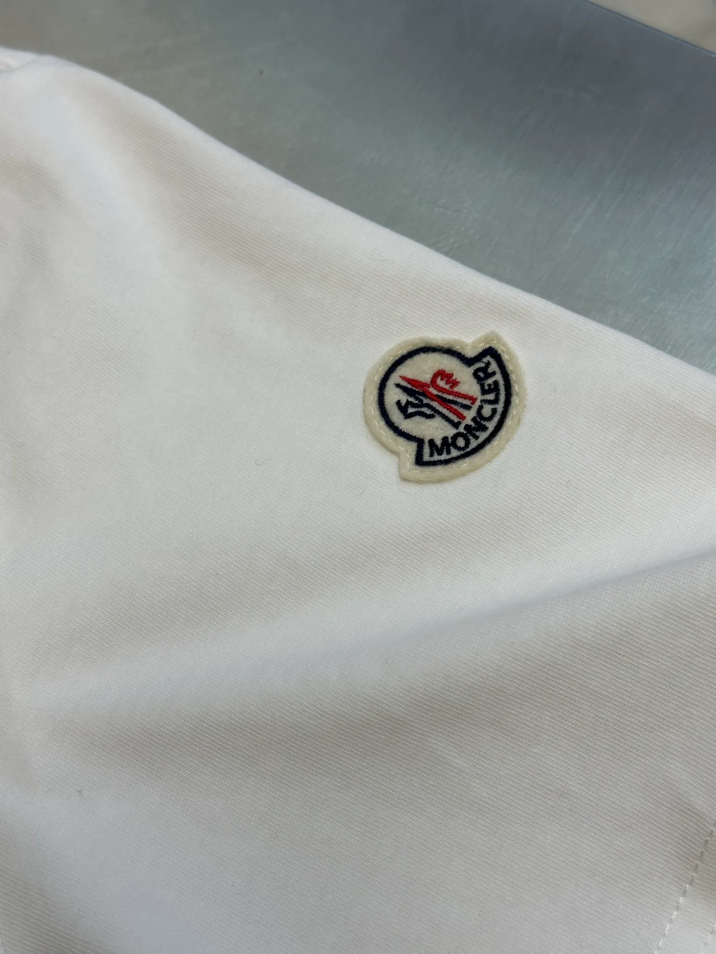 P230 Moncler short-sleeved patch logo, custom-made cloud-soft plain cotton fabric, with the iconic three-color design badge embellished on the chest, interpreting the visual grammar of modern luxury, and the Moncler embroidered logo on the side, highlighting the brand style.  Using imported machine embroidery technology, advanced computer control systems and precision mechanical components, Moncler embroidery logo embroidery operations are realized.  size：s m l xl