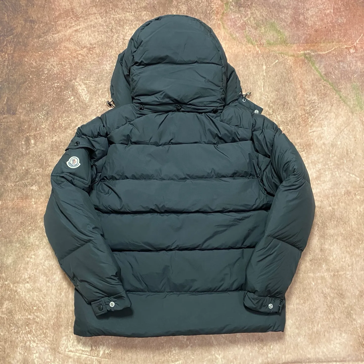 P840 MONCLER matte Maya down jacket. Process description: Made of the brand's iconic longue saison fabric, it has both light texture and excellent thermal insulation performance. This unisex down jacket has a matte appearance and is lined with lon léger brillant material to ensure comfort. Its core filling is 90% high-quality goose down, with a down filling capacity of 204 grams, providing excellent thermal insulation effect. The design continues the classic elements of Moner, with the short silhouette and sleeve patch pocket details paying tribute to the Maya series. In terms of functionality, it is equipped with a detachable and adjustable hood, a dual zipper and snap button opening system, and a zipper pocket to enhance practicality. The sleeves are specially designed with adjustable cuffs and a drawstring hem design, so you can freely adjust the tightness according to your needs. The overall craftsmanship is exquisite, which not only retains Moner's consistent fashion genes, but also enhances the convenience of daily wear through exquisite detail processing. ⚠️Color: Black ⚠️Size: 12345