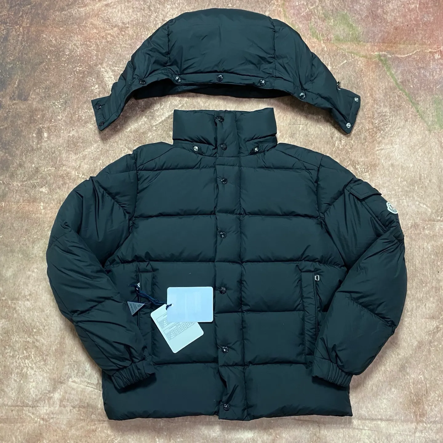 P840 MONCLER matte Maya down jacket. Process description: Made of the brand's iconic longue saison fabric, it has both light texture and excellent thermal insulation performance. This unisex down jacket has a matte appearance and is lined with lon léger brillant material to ensure comfort. Its core filling is 90% high-quality goose down, with a down filling capacity of 204 grams, providing excellent thermal insulation effect. The design continues the classic elements of Moner, with the short silhouette and sleeve patch pocket details paying tribute to the Maya series. In terms of functionality, it is equipped with a detachable and adjustable hood, a dual zipper and snap button opening system, and a zipper pocket to enhance practicality. The sleeves are specially designed with adjustable cuffs and a drawstring hem design, so you can freely adjust the tightness according to your needs. The overall craftsmanship is exquisite, which not only retains Moner's consistent fashion genes, but also enhances the convenience of daily wear through exquisite detail processing. ⚠️Color: Black ⚠️Size: 12345