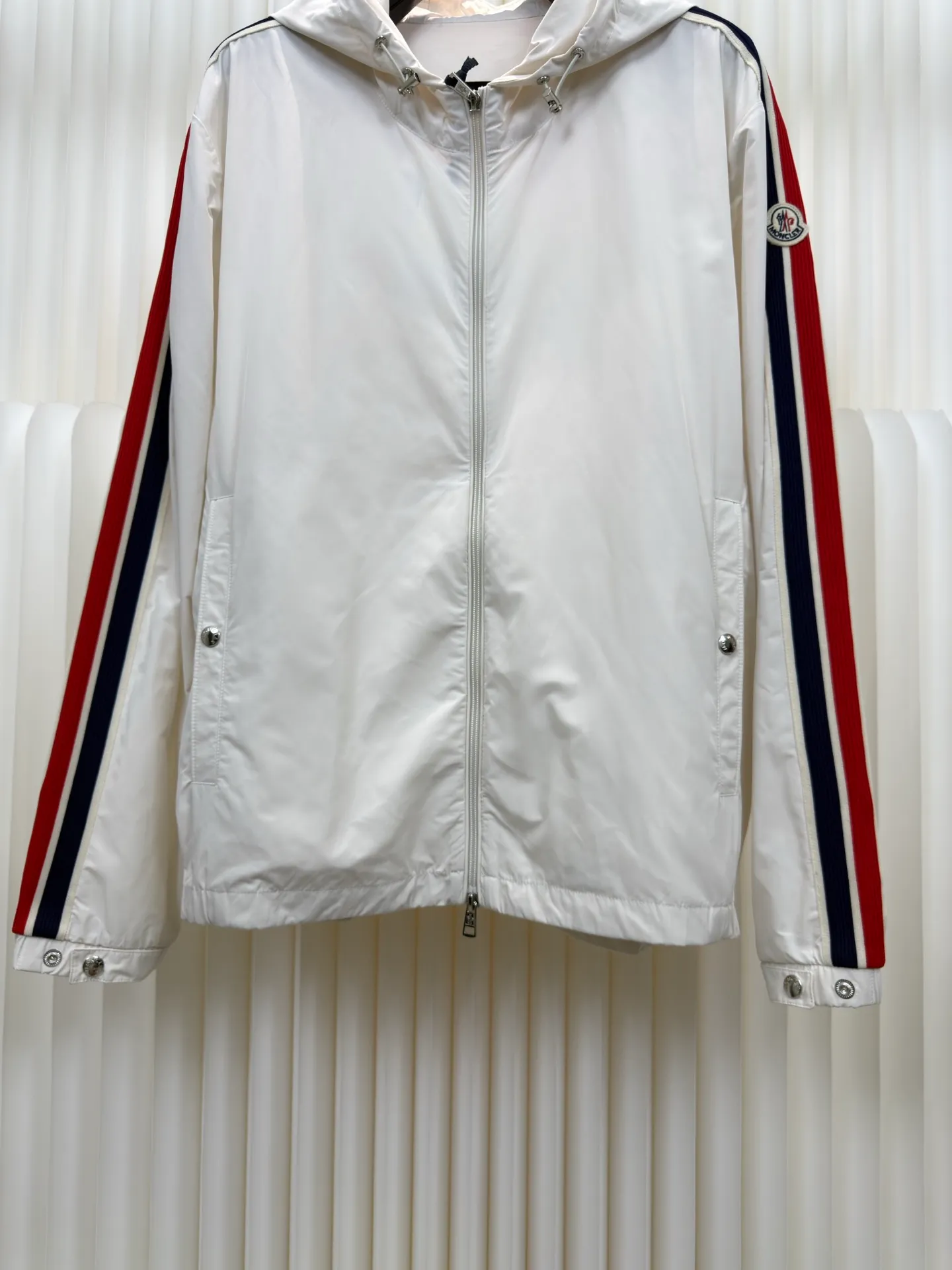 P570 MONCLER lightweight jacket with web trim at the mouth is made of 100% polyester fiber to create a tough protective outer layer. It is famous for its excellent tear resistance and wear resistance. It can quickly return to flatness during wearing and maintain the crisp and stylish appearance of the clothing for a long time. At the same time, it is not easy to deform after being washed for a long time.  Decorative edging in two different colors has been added to the center section of the sleeves. This design element not only adds visual highlights to clothing, making it more fashionable and unique. The webbing is precisely positioned along the cuffs to the seam of the collar and hat to ensure symmetry and overall smoothness. Before actual sewing, use very fine basting stitches for pre-fixing. This step is crucial to prevent the webbing from slipping, twisting, or wrinkling during sewing and ensuring that the final stitch is straight and perfect. Size 1 2 3 4