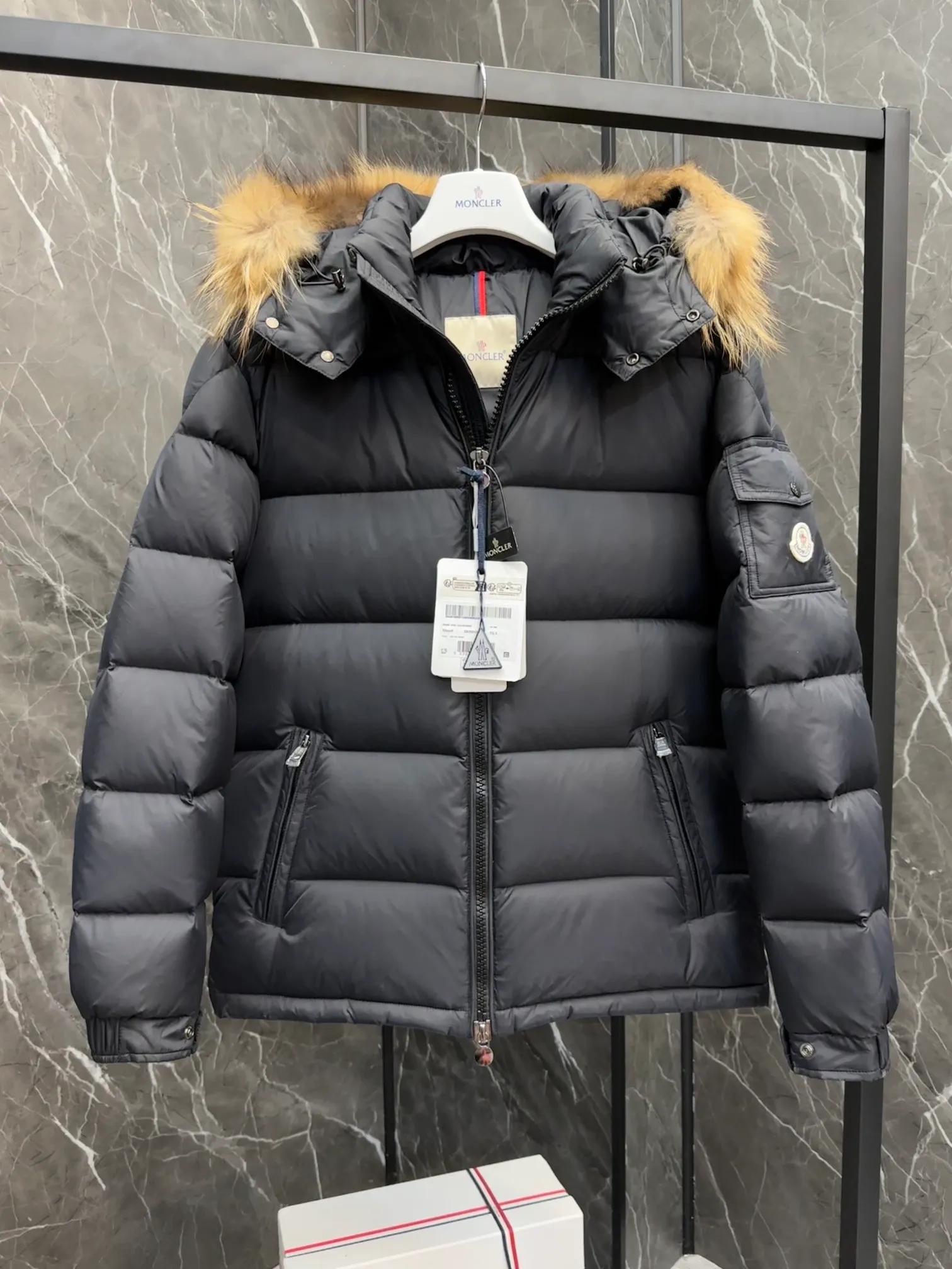 P1040 ⬆️Moncler Mayaf short men's down jacket. The hood is removable. The fur collar is removable. Based on Maya, a removable fur collar is added. The Mayaf men's hooded down jacket is made of functional nylon fabric, and the hood is equipped with removable synthetic material trim.  The Mayaf short down jacket is a reinterpretation of the classic Moncler Maya style in an instantly recognizable silhouette, with a removable hood and adjustable hem. Made from functional fabric with removable synthetic trim on the hood. The sleeves are embellished with classic patch pockets, reflecting the brand's signature style. Details •Made from functional fabric •Technical fabric lining •Down-filled •Push-stud collar •Detachable hood with removable synthetic trim •Zip closure •Zip pockets •Patch pockets with press-stud •Adjustable elastic cuffs •Adjustable drawstring hem