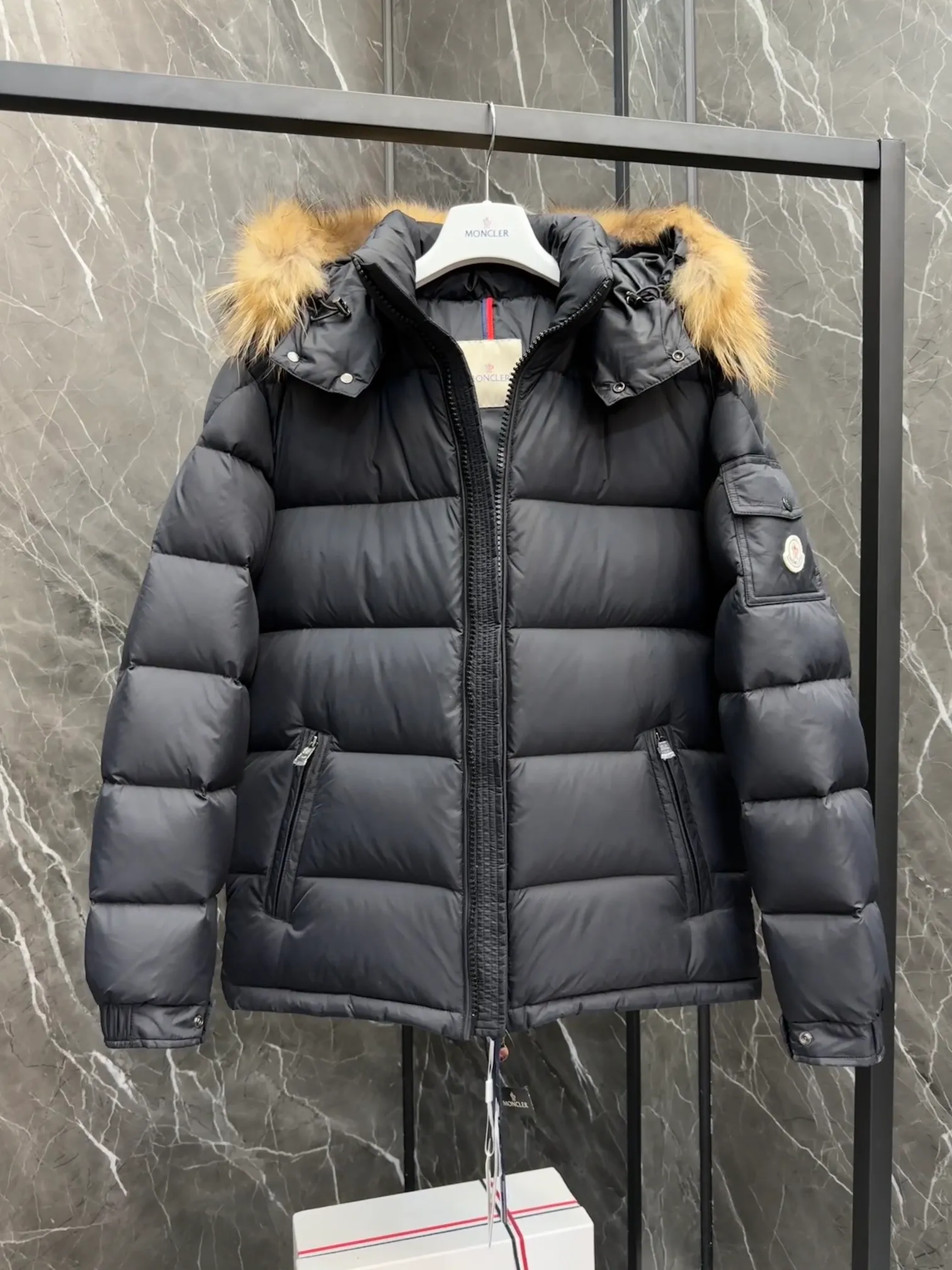 P1040 ⬆️Moncler Mayaf short men's down jacket. The hood is removable. The fur collar is removable. Based on Maya, a removable fur collar is added. The Mayaf men's hooded down jacket is made of functional nylon fabric, and the hood is equipped with removable synthetic material trim.  The Mayaf short down jacket is a reinterpretation of the classic Moncler Maya style in an instantly recognizable silhouette, with a removable hood and adjustable hem. Made from functional fabric with removable synthetic trim on the hood. The sleeves are embellished with classic patch pockets, reflecting the brand's signature style. Details •Made from functional fabric •Technical fabric lining •Down-filled •Push-stud collar •Detachable hood with removable synthetic trim •Zip closure •Zip pockets •Patch pockets with press-stud •Adjustable elastic cuffs •Adjustable drawstring hem