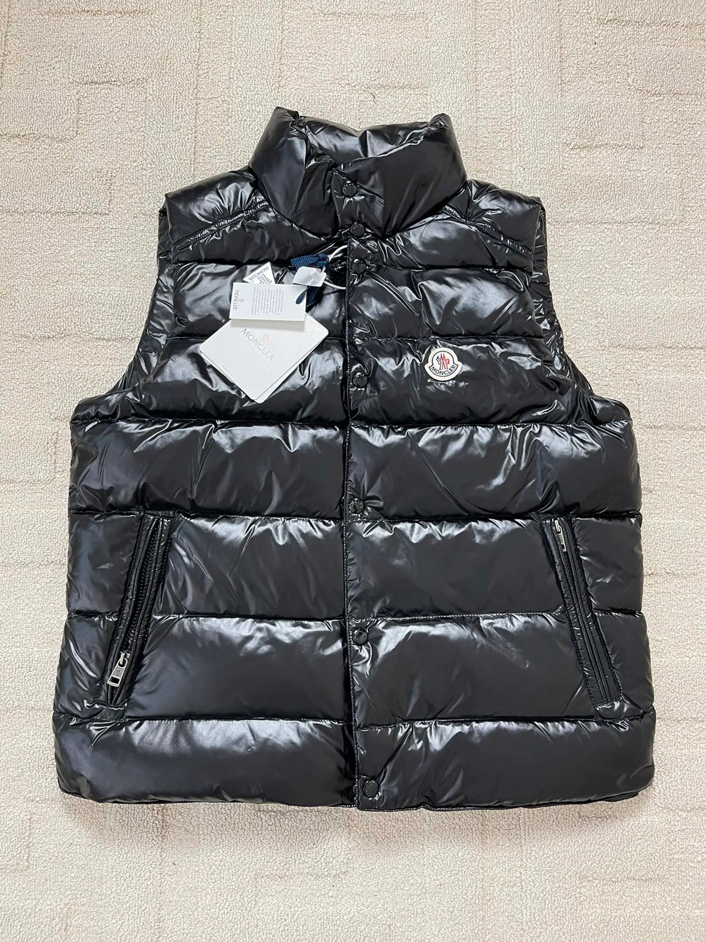 Tile details P820 Moncler Tibb Men's Tibb Vest Vest Down Jacket The Tibb men's vest is Moncler's classic item, inspired by the iconic archive silhouette of the 1980s. Made from nylon laqué fabric, it can be worn as an urban outerwear piece during the changing seasons, or layered over a jacket to complete a look in the colder months.  Fabric: 100% nylon; Lining: 100% nylon; Filling down content: 90% white duck down, 10% feather Filling capacity: 180-200g, Craftsmanship: Made of nylon laqué fabric, Nylon laque lining, down filling, zipper closure, collar with snap closure, zipper pocket, zipper internal pocket Size: 1 2 3 4 5 6 0330020