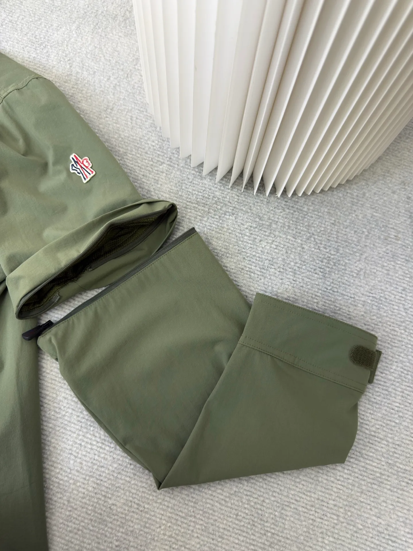 P640 Moncler Grenoble Functional Outdoor Jacket Custom-dyed double-stretch mercerized poplin Custom-dyed soft-mesh pongee Excellent texture Comfortable and close to the skin Dark green inspired by plant texture The color is taken from sage leaves soaked in morning dew Precision narrative of functional pocket system Balance of function and aesthetics The iconic Moncler logo appears on the sleeves, fully recognizable The triangular logo of the same color is hidden in the fabric texture like a mark in the undercurrent of the deep sea Extremely hidden and visible. The detachable sleeve design allows for diversified outfits. You can switch styles at will. Feel free and elegant. Show your dignity. Balance outdoor practicality and urban aesthetics. Lead the fashion. Adopt three-in-one process. Give priority to evenly coating the glue on the surface of the substrate that needs to be composited. Then dry and solidify. Then laminate the substrate with the adhesive film and the non-woven fabric. Then cool and solidify. Then composite the filter non-woven fabric. The workmanship is cumbersome and complex. Time-consuming and labor-intensive. Embossed composite technology Through computer scanning, ensure that the imprint size and shape are consistent with the original. Then use special glue as an adhesive to combine and then solidify to achieve complete dryness and the best bonding effect. Use CNC laser burning and cutting based on the high-energy characteristics of the laser. Precisely control the movement path of the laser beam with a laser generator to achieve precise cutting of the shape of the piece. Template machine bag opening. The preset template guides the position, shape and size of the bag opening. The accuracy ensures the quality of the bag opening effect. Uses infrared special machine to fasten the position more accurately. Strong and sturdy, loose fit, detachable sleeve splicing, style can be switched at will Size: 1 2 3 4