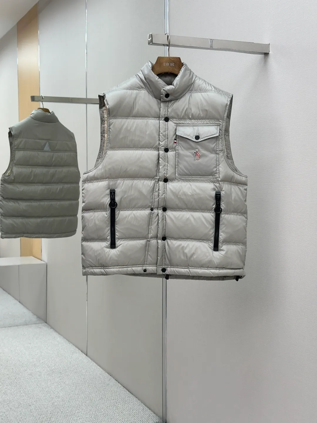 P680 MONCLER down vest with reflective markings Fabric selection: Made of ultra-fine nylon yarn woven in a high-density manner. The number of yarns per unit area is large, and the gaps between the yarns are very small, which can effectively block the penetration of cold wind. The fine weave keeps it lightweight and soft to the touch, physically restricting the lightweight down fibers from slipping through the gaps. Nylon fiber itself has good wear resistance and is not easy to snag, which significantly extends its service life and can easily cope with the needs of multiple scenarios.  Lining selection: The lining is made of 100% polyester fiber high-density weaving. The thickness of 0.08mm avoids increasing the overall weight and makes it smooth to wear. The high-density weaving structure forms a wind resistance layer to protect the thermal efficiency of the thermal insulation layer from loss. At the same time, it can withstand the expansion pressure of down and prevent deformation and damage after long-term use.  High-quality filling: 90 white duck down is selected, with a weight of 130g, ensuring excellent thermal insulation performance. After strict screening and processing, the velvet is not easy to get drilled, ensuring durability.  Process: Through the reflective cloth punching process, the logo is regularly arranged on the triangular reflective mark with dozens of small holes, which not only improves the functionality, but also strengthens the recognition and aesthetics.   Accessories: Customized snap buttons, customized zipper pullers, customized badges, customized elastic buckles, etc. SIZE: 1 2 3 4