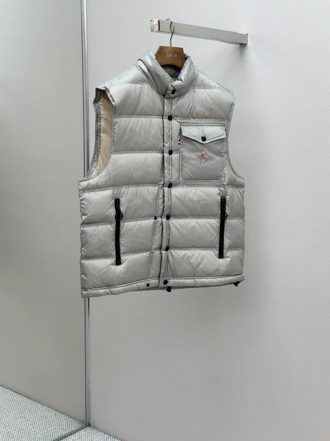 P680 MONCLER down vest with reflective markings Fabric selection: Made of ultra-fine nylon yarn woven in a high-density manner. The number of yarns per unit area is large, and the gaps between the yarns are very small, which can effectively block the penetration of cold wind. The fine weave keeps it lightweight and soft to the touch, physically restricting the lightweight down fibers from slipping through the gaps. Nylon fiber itself has good wear resistance and is not easy to snag, which significantly extends its service life and can easily cope with the needs of multiple scenarios.  Lining selection: The lining is made of 100% polyester fiber high-density weaving. The thickness of 0.08mm avoids increasing the overall weight and makes it smooth to wear. The high-density weaving structure forms a wind resistance layer to protect the thermal efficiency of the thermal insulation layer from loss. At the same time, it can withstand the expansion pressure of down and prevent deformation and damage after long-term use.  High-quality filling: 90 white duck down is selected, with a weight of 130g, ensuring excellent thermal insulation performance. After strict screening and processing, the velvet is not easy to get drilled, ensuring durability.  Process: Through the reflective cloth punching process, the logo is regularly arranged on the triangular reflective mark with dozens of small holes, which not only improves the functionality, but also strengthens the recognition and aesthetics.   Accessories: Customized snap buttons, customized zipper pullers, customized badges, customized elastic buckles, etc. SIZE: 1 2 3 4