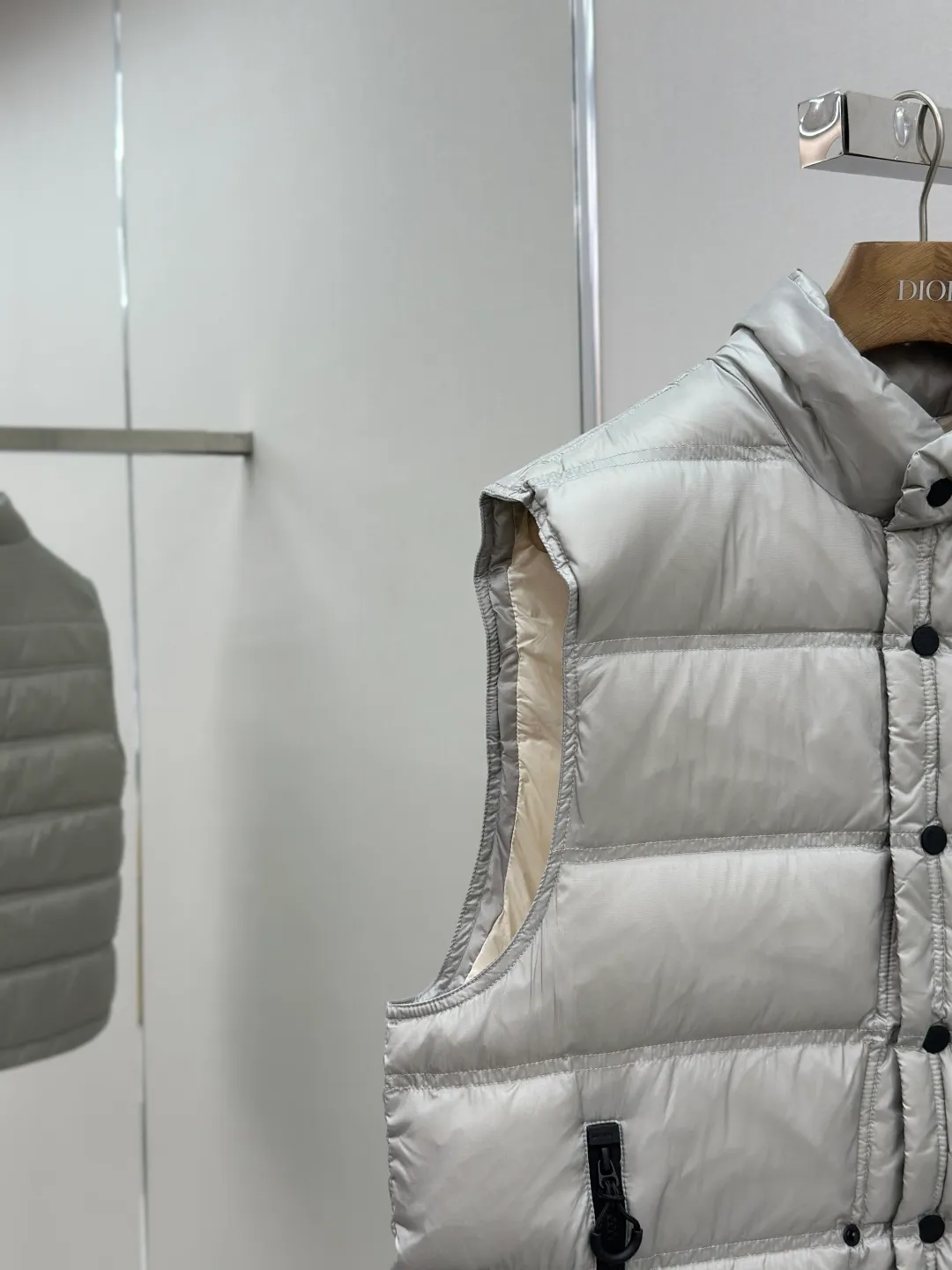 P680 MONCLER down vest with reflective markings Fabric selection: Made of ultra-fine nylon yarn woven in a high-density manner. The number of yarns per unit area is large, and the gaps between the yarns are very small, which can effectively block the penetration of cold wind. The fine weave keeps it lightweight and soft to the touch, physically restricting the lightweight down fibers from slipping through the gaps. Nylon fiber itself has good wear resistance and is not easy to snag, which significantly extends its service life and can easily cope with the needs of multiple scenarios.  Lining selection: The lining is made of 100% polyester fiber high-density weaving. The thickness of 0.08mm avoids increasing the overall weight and makes it smooth to wear. The high-density weaving structure forms a wind resistance layer to protect the thermal efficiency of the thermal insulation layer from loss. At the same time, it can withstand the expansion pressure of down and prevent deformation and damage after long-term use.  High-quality filling: 90 white duck down is selected, with a weight of 130g, ensuring excellent thermal insulation performance. After strict screening and processing, the velvet is not easy to get drilled, ensuring durability.  Process: Through the reflective cloth punching process, the logo is regularly arranged on the triangular reflective mark with dozens of small holes, which not only improves the functionality, but also strengthens the recognition and aesthetics.   Accessories: Customized snap buttons, customized zipper pullers, customized badges, customized elastic buckles, etc. SIZE: 1 2 3 4
