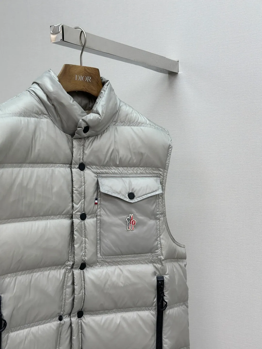 P680 MONCLER down vest with reflective markings Fabric selection: Made of ultra-fine nylon yarn woven in a high-density manner. The number of yarns per unit area is large, and the gaps between the yarns are very small, which can effectively block the penetration of cold wind. The fine weave keeps it lightweight and soft to the touch, physically restricting the lightweight down fibers from slipping through the gaps. Nylon fiber itself has good wear resistance and is not easy to snag, which significantly extends its service life and can easily cope with the needs of multiple scenarios.  Lining selection: The lining is made of 100% polyester fiber high-density weaving. The thickness of 0.08mm avoids increasing the overall weight and makes it smooth to wear. The high-density weaving structure forms a wind resistance layer to protect the thermal efficiency of the thermal insulation layer from loss. At the same time, it can withstand the expansion pressure of down and prevent deformation and damage after long-term use.  High-quality filling: 90 white duck down is selected, with a weight of 130g, ensuring excellent thermal insulation performance. After strict screening and processing, the velvet is not easy to get drilled, ensuring durability.  Process: Through the reflective cloth punching process, the logo is regularly arranged on the triangular reflective mark with dozens of small holes, which not only improves the functionality, but also strengthens the recognition and aesthetics.   Accessories: Customized snap buttons, customized zipper pullers, customized badges, customized elastic buckles, etc. SIZE: 1 2 3 4