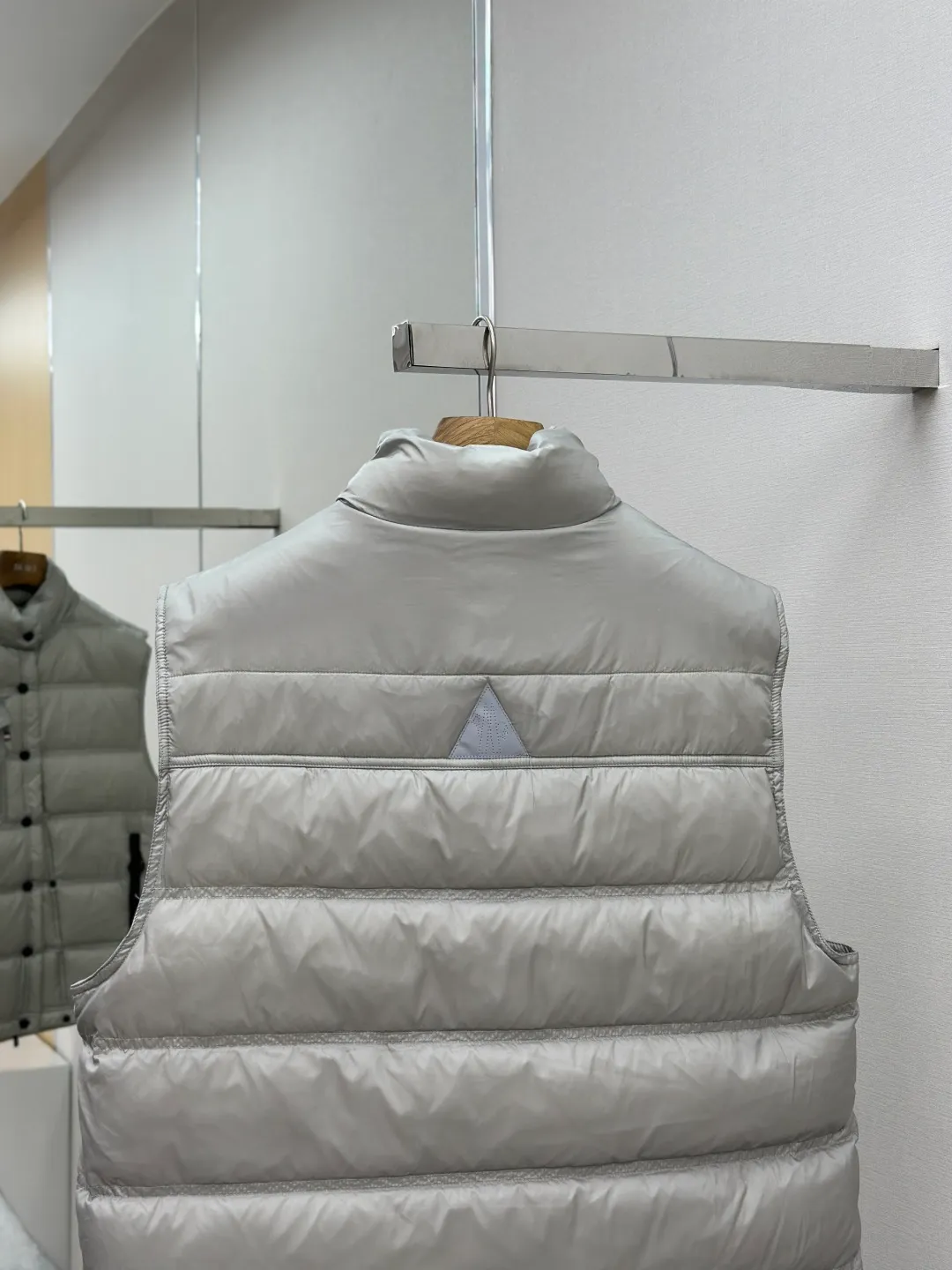 P680 MONCLER down vest with reflective markings Fabric selection: Made of ultra-fine nylon yarn woven in a high-density manner. The number of yarns per unit area is large, and the gaps between the yarns are very small, which can effectively block the penetration of cold wind. The fine weave keeps it lightweight and soft to the touch, physically restricting the lightweight down fibers from slipping through the gaps. Nylon fiber itself has good wear resistance and is not easy to snag, which significantly extends its service life and can easily cope with the needs of multiple scenarios.  Lining selection: The lining is made of 100% polyester fiber high-density weaving. The thickness of 0.08mm avoids increasing the overall weight and makes it smooth to wear. The high-density weaving structure forms a wind resistance layer to protect the thermal efficiency of the thermal insulation layer from loss. At the same time, it can withstand the expansion pressure of down and prevent deformation and damage after long-term use.  High-quality filling: 90 white duck down is selected, with a weight of 130g, ensuring excellent thermal insulation performance. After strict screening and processing, the velvet is not easy to get drilled, ensuring durability.  Process: Through the reflective cloth punching process, the logo is regularly arranged on the triangular reflective mark with dozens of small holes, which not only improves the functionality, but also strengthens the recognition and aesthetics.   Accessories: Customized snap buttons, customized zipper pullers, customized badges, customized elastic buckles, etc. SIZE: 1 2 3 4