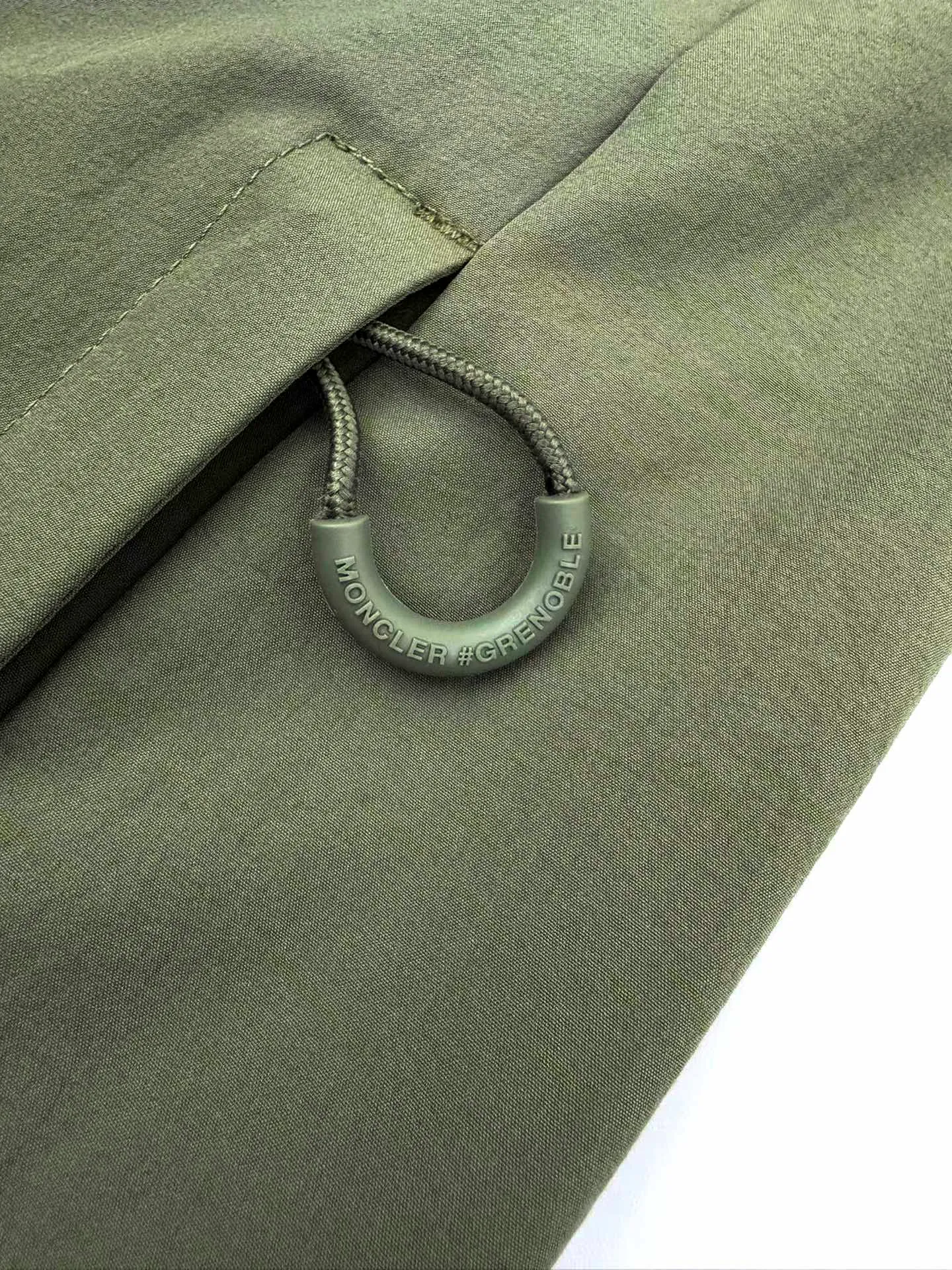 P610 Moncler Grenoble functional outdoor jacket Custom-dyed double-stretch mercerized poplin Custom-dyed soft mesh pongee Excellent texture Comfortable and close to the skin Dark green inspired by plant texture The color is taken from sage leaves soaked in morning dew Precision narrative of functional pocket system Balance of function and aesthetics The iconic Moncler logo appears on the sleeves for full recognition The triangular logo of the same color is hidden in the fabric texture like a mark in the undercurrent of the deep sea, extremely invisible and yet obvious The detachable sleeve design allows for diversified outfits. You can switch styles at will. It is chic and free, showing nobility. It balances outdoor practicality and urban aesthetics and leads the fashion. Process 1: Adopt a three-in-one process. Prioritize and evenly coat the glue on the surface of the substrate that needs to be composited, and then dry and solidify it. Then laminate the substrate with the adhesive film and the non-woven fabric, then cool and solidify, and then composite it with the filter non-woven fabric. The workmanship is cumbersome and complex, time-consuming and labor-intensive. Process 2: Embossing composite technology uses computer scanning to ensure that the imprint size and shape are consistent with the original, and then uses special glue as an adhesive to combine and solidify to achieve complete dryness and the best bonding effect. Process 3: Use CNC laser burning and cutting. Based on the high-energy characteristics of the laser, the moving path of the laser beam is precisely controlled by the laser generator to achieve precise cutting of the shape of the piece. Process 4: Template machine bag opening. The preset template guides the position, shape and size of the bag opening. The accuracy ensures the quality of the bag opening effect. Process 5: Using infrared special machine buttoning, the position is more precise and strong. Accessories: Customized 1:1 Moncler snap button Customized 1:1 Moncler resin buckle Customized 1:1 Moncler logo seal Customized 1:1 Moncler logo armband Customized 1:1 Moncler zipper rope ring Customized 1:1 Moncler zipper pull Customized 1:1 Moncler trademark Version: Loose version Function: Detachable sleeve splicing Style can be switched at will Size: 1 2 3 4