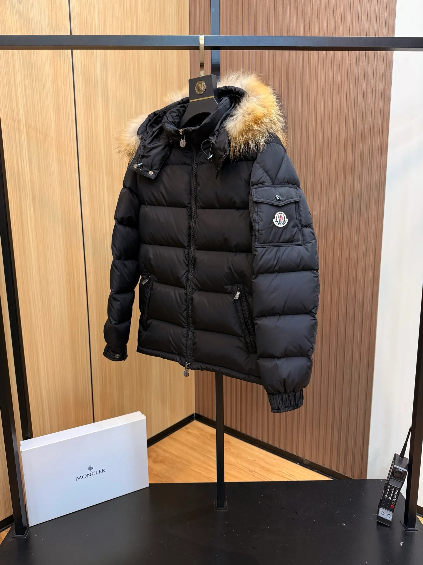 P1000 Moncler Mayaf short men's down jacket jacket. The hood is removable. The fur collar is removable. Based on Maya, a removable fur collar is added. The Mayaf men's hooded down jacket is made of functional nylon fabric, and the hood is equipped with removable synthetic material trim.  The Mayaf short down jacket is a reinterpretation of the classic Moncler Maya style in an instantly recognizable silhouette, with a removable hood and adjustable hem. Made from functional fabric with removable synthetic trim on the hood. The sleeves are embellished with classic patch pockets, reflecting the brand's signature style. Details •Made from functional fabric •Technical fabric lining •Down-filled •Push-stud collar •Detachable hood with removable synthetic trim •Zip closure •Zip pockets •Patch pockets with press-stud •Adjustable elastic cuffs •Adjustable drawstring hem