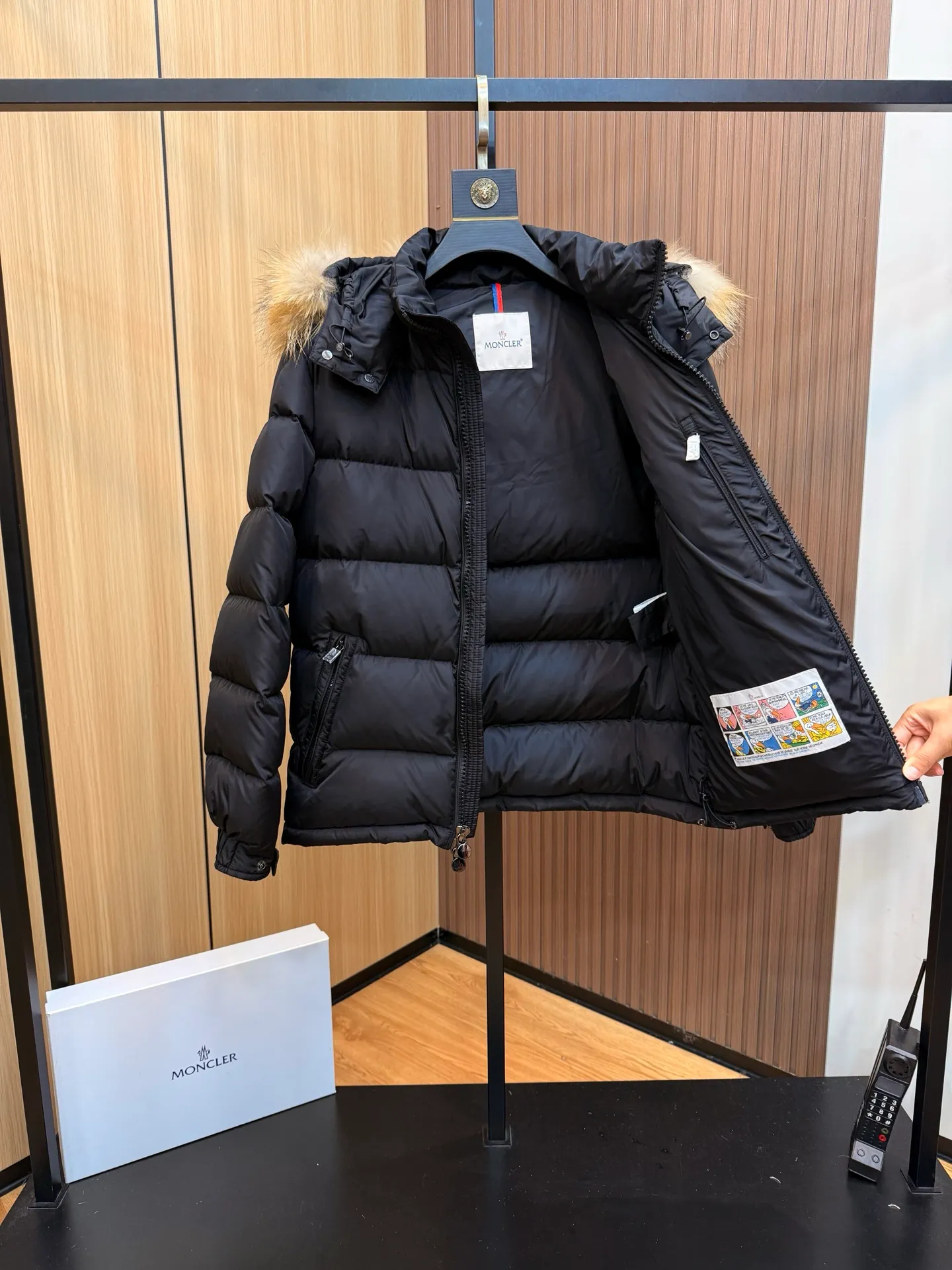 P1000 Moncler Mayaf short men's down jacket jacket. The hood is removable. The fur collar is removable. Based on Maya, a removable fur collar is added. The Mayaf men's hooded down jacket is made of functional nylon fabric, and the hood is equipped with removable synthetic material trim.  The Mayaf short down jacket is a reinterpretation of the classic Moncler Maya style in an instantly recognizable silhouette, with a removable hood and adjustable hem. Made from functional fabric with removable synthetic trim on the hood. The sleeves are embellished with classic patch pockets, reflecting the brand's signature style. Details •Made from functional fabric •Technical fabric lining •Down-filled •Push-stud collar •Detachable hood with removable synthetic trim •Zip closure •Zip pockets •Patch pockets with press-stud •Adjustable elastic cuffs •Adjustable drawstring hem