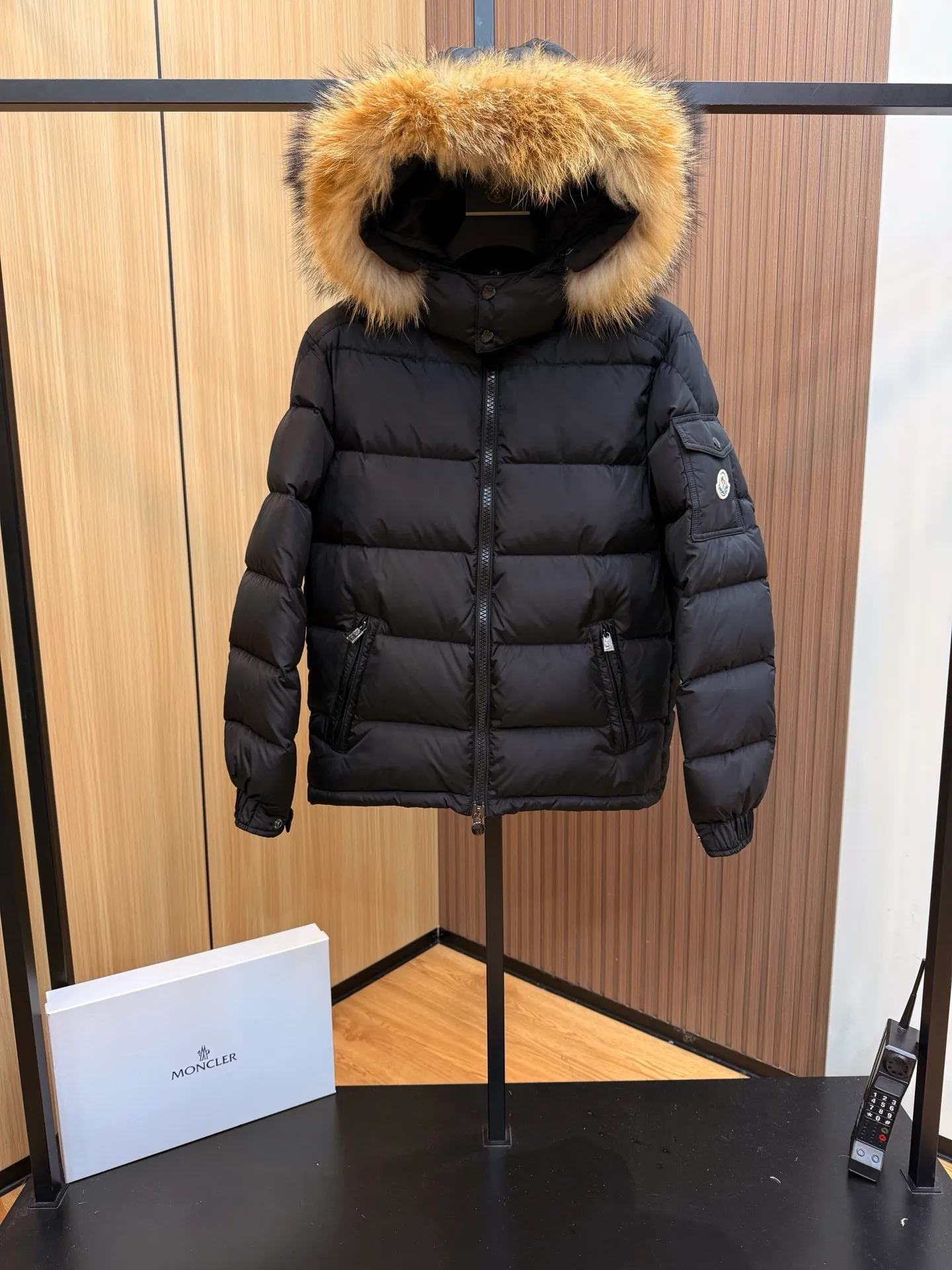 P1000 Moncler Mayaf short men's down jacket jacket. The hood is removable. The fur collar is removable. Based on Maya, a removable fur collar is added. The Mayaf men's hooded down jacket is made of functional nylon fabric, and the hood is equipped with removable synthetic material trim.  The Mayaf short down jacket is a reinterpretation of the classic Moncler Maya style in an instantly recognizable silhouette, with a removable hood and adjustable hem. Made from functional fabric with removable synthetic trim on the hood. The sleeves are embellished with classic patch pockets, reflecting the brand's signature style. Details •Made from functional fabric •Technical fabric lining •Down-filled •Push-stud collar •Detachable hood with removable synthetic trim •Zip closure •Zip pockets •Patch pockets with press-stud •Adjustable elastic cuffs •Adjustable drawstring hem