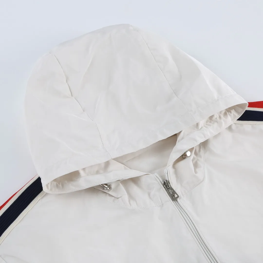 P540 MONCLER web-trimmed lightweight jacket Fabric selection: 100% polyester fiber is used to create a tough protective outer layer. It is known for its excellent tear resistance and wear resistance. It can quickly return to flatness during wearing and maintain the crisp and stylish appearance of the clothing for a long time. At the same time, it is not easy to deform after being washed for a long time.   Features: Two different colored decorative strips added to the center part of the sleeves. This design element can not only add visual highlights to clothing, making it more fashionable and unique. Craftsmanship: The webbing is precisely positioned along the cuffs to the seam of the collar and hat to ensure symmetry and overall smoothness. Before actual sewing, use very fine basting stitches for pre-fixing. This step is crucial to prevent the webbing from slipping, twisting, or wrinkling during sewing and ensuring that the final stitch is straight and perfect.  Accessories: 1:1 customized zipper puller, 1:1 customized buttons with logo, 1:1 customized hood drawstring elastic buckle SIZE: 1 2 3 4