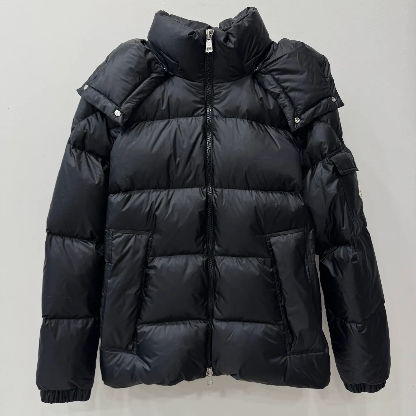 P1100 Brand: Moncler Filling: 90 white duck down Weight: 380-450 Color: White Black Gray Size: 12345 [Couyere Men's Hooded Short Down Jacket] The Couyere short down jacket is durable and practical, provides functional warmth and care, and will accompany you to meet challenges.  The Couyere is a durable down jacket made from a fine fabric that's durable and functional, with velvet resistance and functionality. The short design creates a sculpted silhouette, and padded pockets add a modern feel. The sleeves are embellished with signature patch pockets, a nod to the classic Moncler Maya down jacket.  • Made of fine ripstop fabric • Fine fabric lining • Down filling • Detachable and adjustable hood • Zip closure • Zippered pockets • Press-studs on sleeve pockets • Elastic cuffs • Drawstring hem Fabric: 100% nylon; Lining: 100% nylon; Filling: Goose down Down content: 90%; except upholstery; Maximum wash temperature 30°C - Mild wash; Do not bleach; Do not tumble dry; Ironing maximum temperature 110°C - without steam; Hydrocarbon dry cleaning - gentle wash; Professional wet cleaning - gentle wash; Lay flat to dry in shade; Wash separately; Remove removable accessories before washing; Recommend washing and ironing inside out