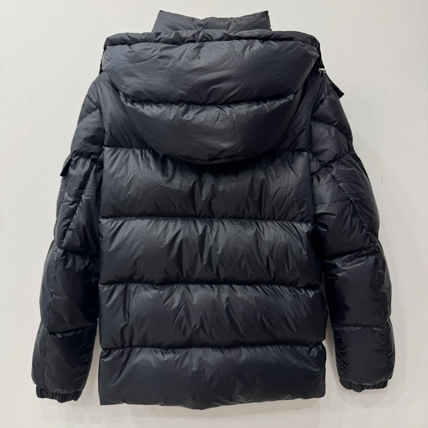 P1100 Brand: Moncler Filling: 90 white duck down Weight: 380-450 Color: White Black Gray Size: 12345 [Couyere Men's Hooded Short Down Jacket] The Couyere short down jacket is durable and practical, provides functional warmth and care, and will accompany you to meet challenges.  The Couyere is a durable down jacket made from a fine fabric that's durable and functional, with velvet resistance and functionality. The short design creates a sculpted silhouette, and padded pockets add a modern feel. The sleeves are embellished with signature patch pockets, a nod to the classic Moncler Maya down jacket.  • Made of fine ripstop fabric • Fine fabric lining • Down filling • Detachable and adjustable hood • Zip closure • Zippered pockets • Press-studs on sleeve pockets • Elastic cuffs • Drawstring hem Fabric: 100% nylon; Lining: 100% nylon; Filling: Goose down Down content: 90%; except upholstery; Maximum wash temperature 30°C - Mild wash; Do not bleach; Do not tumble dry; Ironing maximum temperature 110°C - without steam; Hydrocarbon dry cleaning - gentle wash; Professional wet cleaning - gentle wash; Lay flat to dry in shade; Wash separately; Remove removable accessories before washing; Recommend washing and ironing inside out