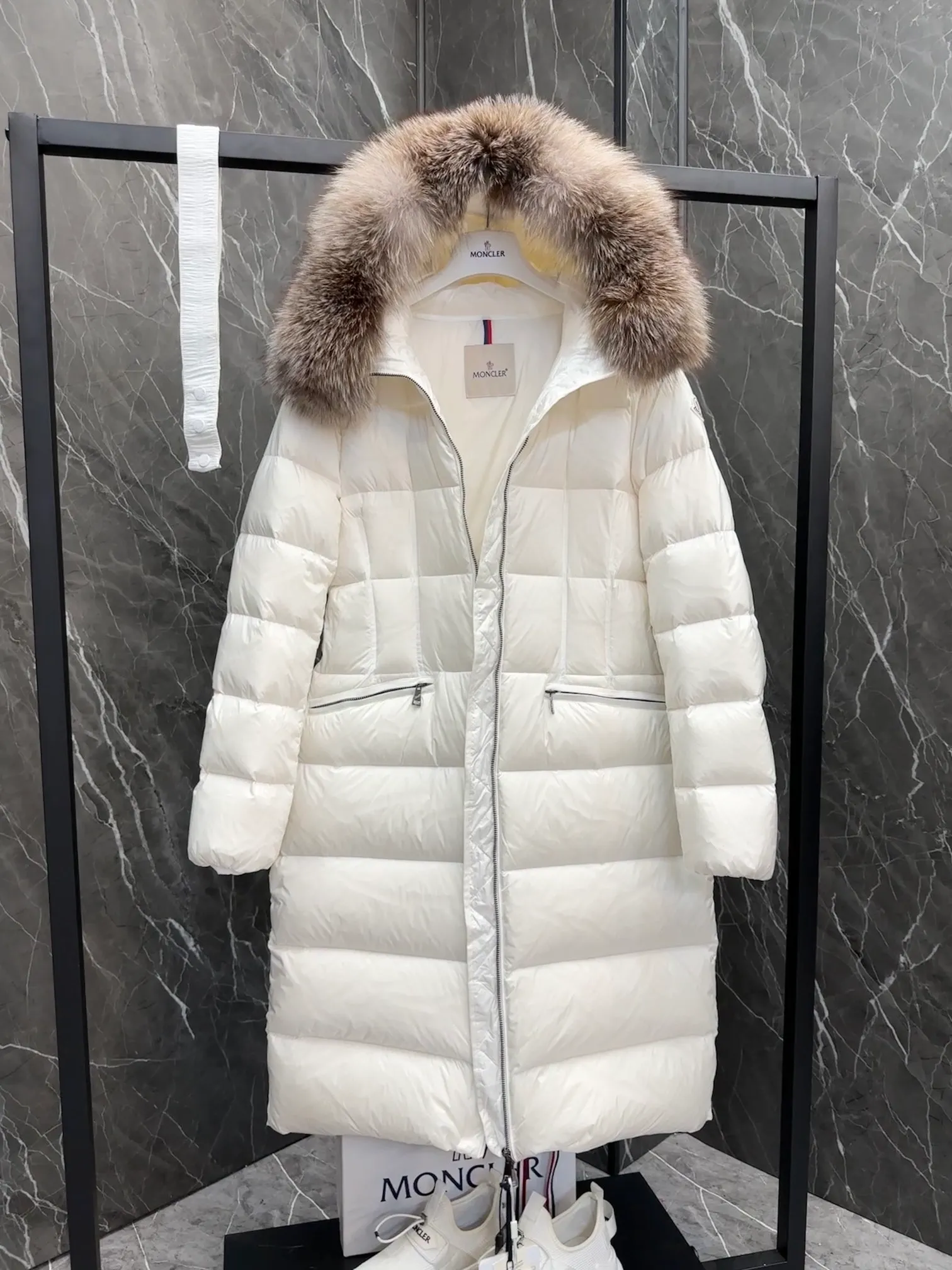 P1020 Moncler Boedic long down jacket for women. (Classic fox fur collar) adopts a whole fox fur collar imported from Finland. The Boedic long down jacket combines exquisite materials and attention to details. The timeless and elegant fashion design can provide you with a warm and caring wearing experience.  Boedic's long down jacket features a waist-cinching belt to accentuate its feminine silhouette for a stylish winter look. The cozy hood has rich fleece trim and is easily removable to suit your mood and weather conditions. Details •Made from lounge saison fabric •Longue saison lining •Filled with down •Hood with removable fox fur collar trim •Two-way zip closure •Elastic waistband with snap button closure •Zip pockets with grosgrain detail •Elastic cuffs Size : 1-4