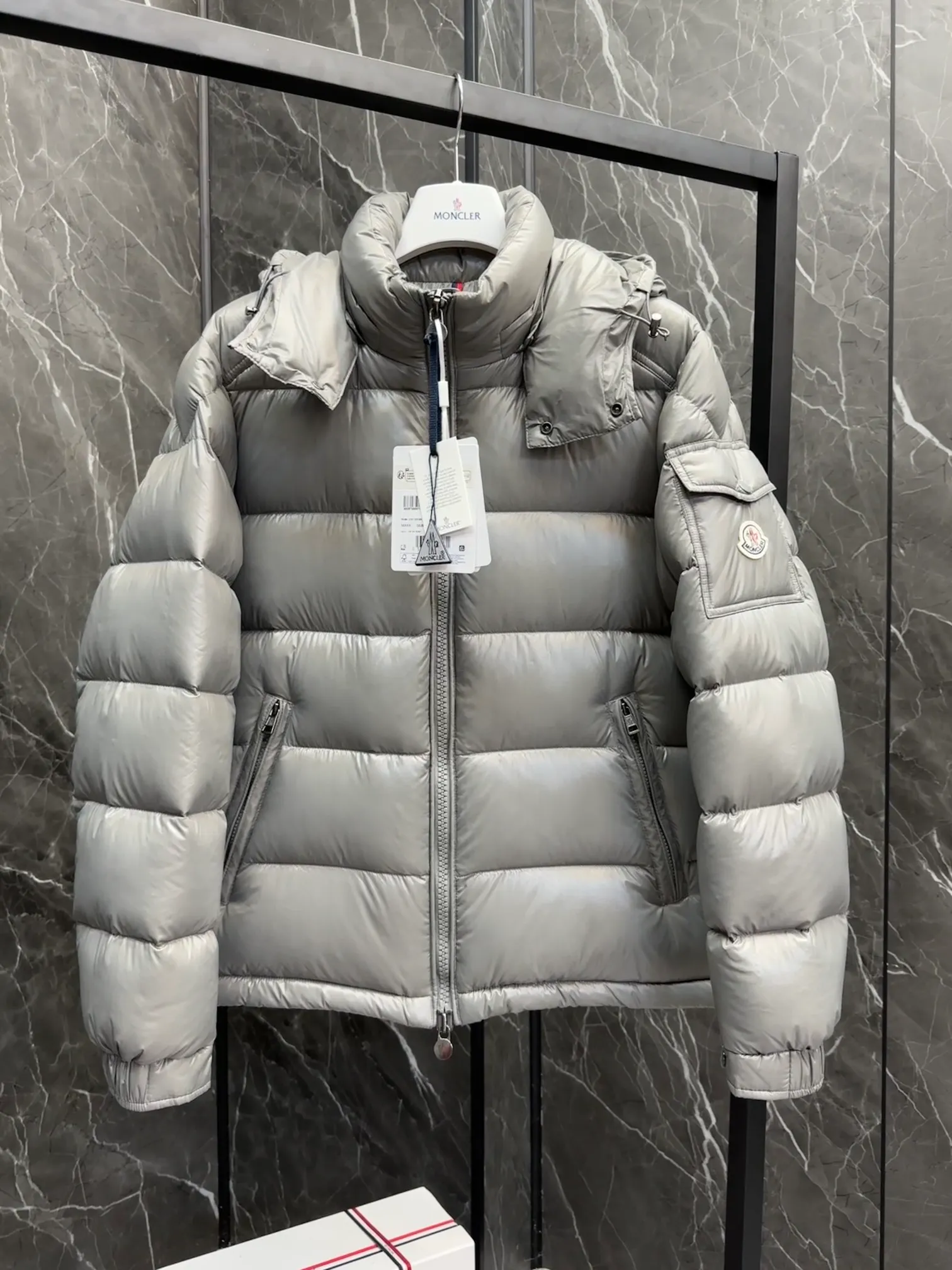 P700 Premium Down ⬆️Moncler Maya classic short down jacket. ⚠️Limited to gray, the only matching color on the market, filled with premium goose down. Try this color on, I guarantee you won’t be able to take it off, it’s too high-end. The Moncler Maya short down jacket is a classic Moncler item, and its style is highly recognizable. Made of lacquered nylon and available in a variety of colors, it's a stylish piece for casual commuting.  The Moncler Maya men's down jacket in shiny patent nylon with signature rectangular quilting is the epitome of Moncler style. A classic cropped design that transcends seasons and styles, it features a statement silhouette, removable hood and adjustable hem. The cuffs are embellished with classic patch pockets, showcasing the brand's signature style. Details • Made of patented nylon • Lacquered nylon lining • Filled with down, rectangular quilting • Detachable hood with snap buttons and drawstring adjustment • Two-way zipper fly • External and internal zippered pockets • Adjustable elastic cuffs with press studs • Drawstring on hood • Flap patch pockets on sleeves • Moncler felt logo on sleeves Size: 1-8 Premium Gray Couple Style.