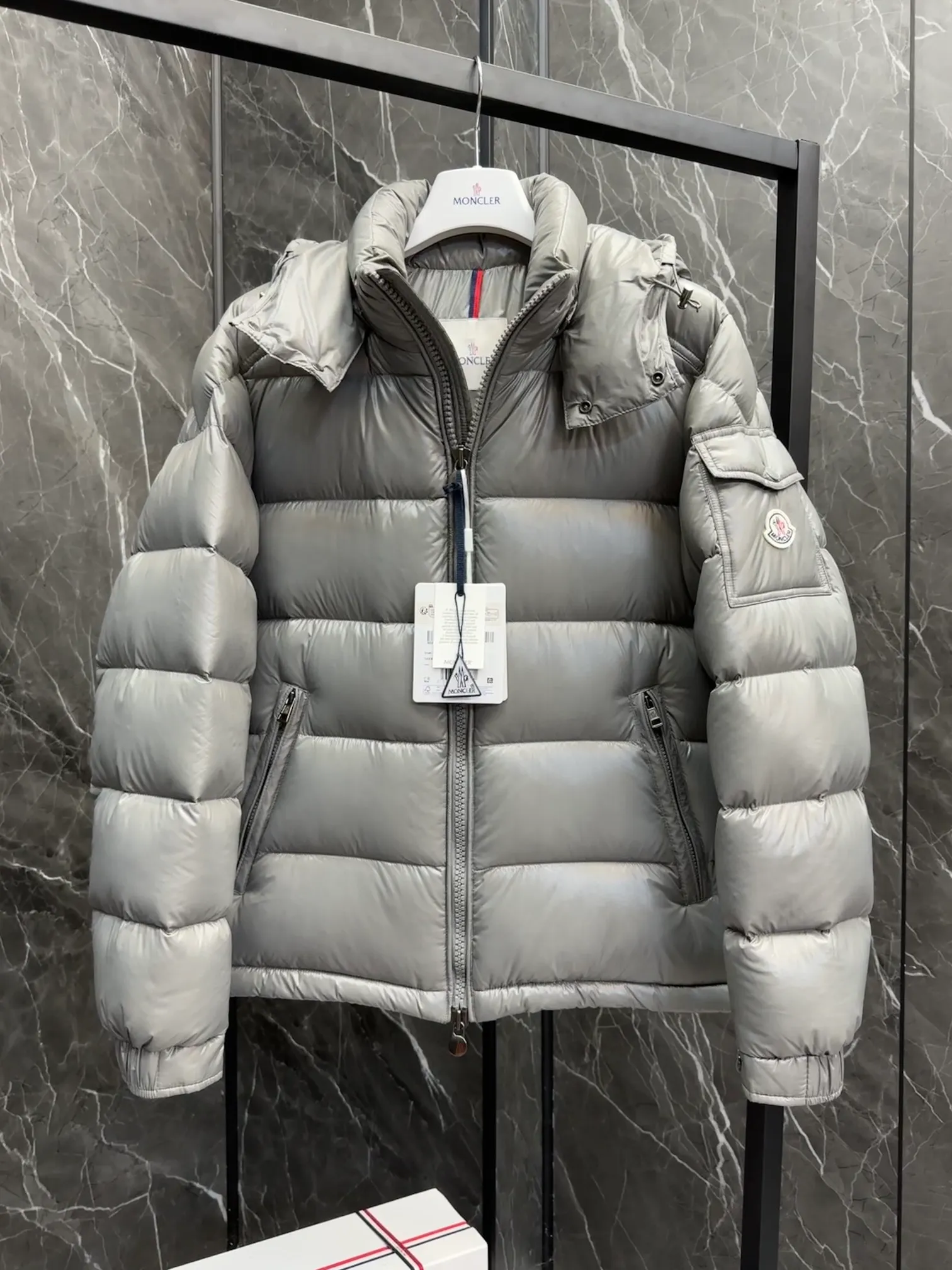 P700 Premium Down ⬆️Moncler Maya classic short down jacket. ⚠️Limited to gray, the only matching color on the market, filled with premium goose down. Try this color on, I guarantee you won’t be able to take it off, it’s too high-end. The Moncler Maya short down jacket is a classic Moncler item, and its style is highly recognizable. Made of lacquered nylon and available in a variety of colors, it's a stylish piece for casual commuting.  The Moncler Maya men's down jacket in shiny patent nylon with signature rectangular quilting is the epitome of Moncler style. A classic cropped design that transcends seasons and styles, it features a statement silhouette, removable hood and adjustable hem. The cuffs are embellished with classic patch pockets, showcasing the brand's signature style. Details • Made of patented nylon • Lacquered nylon lining • Filled with down, rectangular quilting • Detachable hood with snap buttons and drawstring adjustment • Two-way zipper fly • External and internal zippered pockets • Adjustable elastic cuffs with press studs • Drawstring on hood • Flap patch pockets on sleeves • Moncler felt logo on sleeves Size: 1-8 Premium Gray Couple Style.
