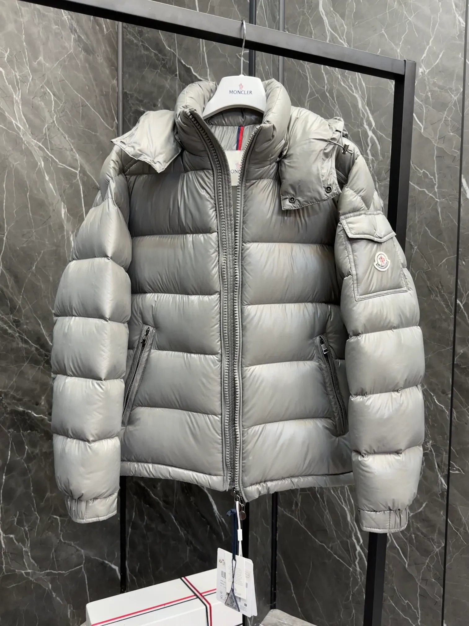 P700 Premium Down ⬆️Moncler Maya classic short down jacket. ⚠️Limited to gray, the only matching color on the market, filled with premium goose down. Try this color on, I guarantee you won’t be able to take it off, it’s too high-end. The Moncler Maya short down jacket is a classic Moncler item, and its style is highly recognizable. Made of lacquered nylon and available in a variety of colors, it's a stylish piece for casual commuting.  The Moncler Maya men's down jacket in shiny patent nylon with signature rectangular quilting is the epitome of Moncler style. A classic cropped design that transcends seasons and styles, it features a statement silhouette, removable hood and adjustable hem. The cuffs are embellished with classic patch pockets, showcasing the brand's signature style. Details • Made of patented nylon • Lacquered nylon lining • Filled with down, rectangular quilting • Detachable hood with snap buttons and drawstring adjustment • Two-way zipper fly • External and internal zippered pockets • Adjustable elastic cuffs with press studs • Drawstring on hood • Flap patch pockets on sleeves • Moncler felt logo on sleeves Size: 1-8 Premium Gray Couple Style.