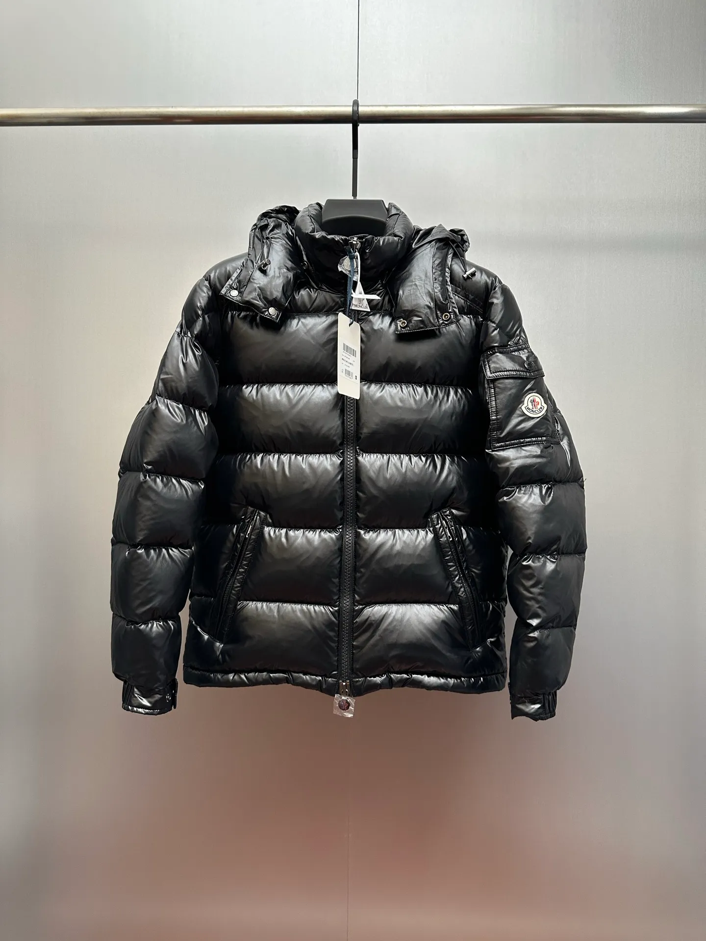 P1040 Premium down ⬆️ Moncler Maya short men's down jacket jacket. Classic Maya (latest purchase counter 2025) The latest classic fabrics are on sale at the counter. ⚠️Maya is a classic series at the counter. Every year there are minor changes. Change the soup without changing the medicine. Not to save development costs, only the latest and best. The Moncler Maya short down jacket is a classic Moncler item, with a highly recognizable style. Made of lacquered nylon and available in many colors, it is a fashionable item for casual commuting and a popular product.  The Moncler Maya men's down jacket in shiny patent nylon with signature rectangular quilting is the epitome of Moncler style. A classic cropped design that transcends seasons and styles, it features a statement silhouette, removable hood and adjustable hem. The cuffs are embellished with classic patch pockets, showcasing the brand's signature style. Details •Made from patented nylon •Painted nylon lining •Down-filled, rectangular quilting •Detachable hood with snap fastening and drawstring adjustment •Two-way zip fly •Exterior and internal zippered pockets •Adjustable elastic cuffs with press-stud •Drawstring at hood •Flap patch pockets at sleeves •Moncler felt logo on sleeves Exclusive quality, hanging at home, five-layer anti-counterfeiting verification, NFC armband chip identification ➕NFC label washing chip identification ➕Elevator scan code verification ➕Washing label scan code verification ➕tag electronic anti-counterfeiting verification❗️❗️❗️ Color: Black Size: 1-6. Couple style
