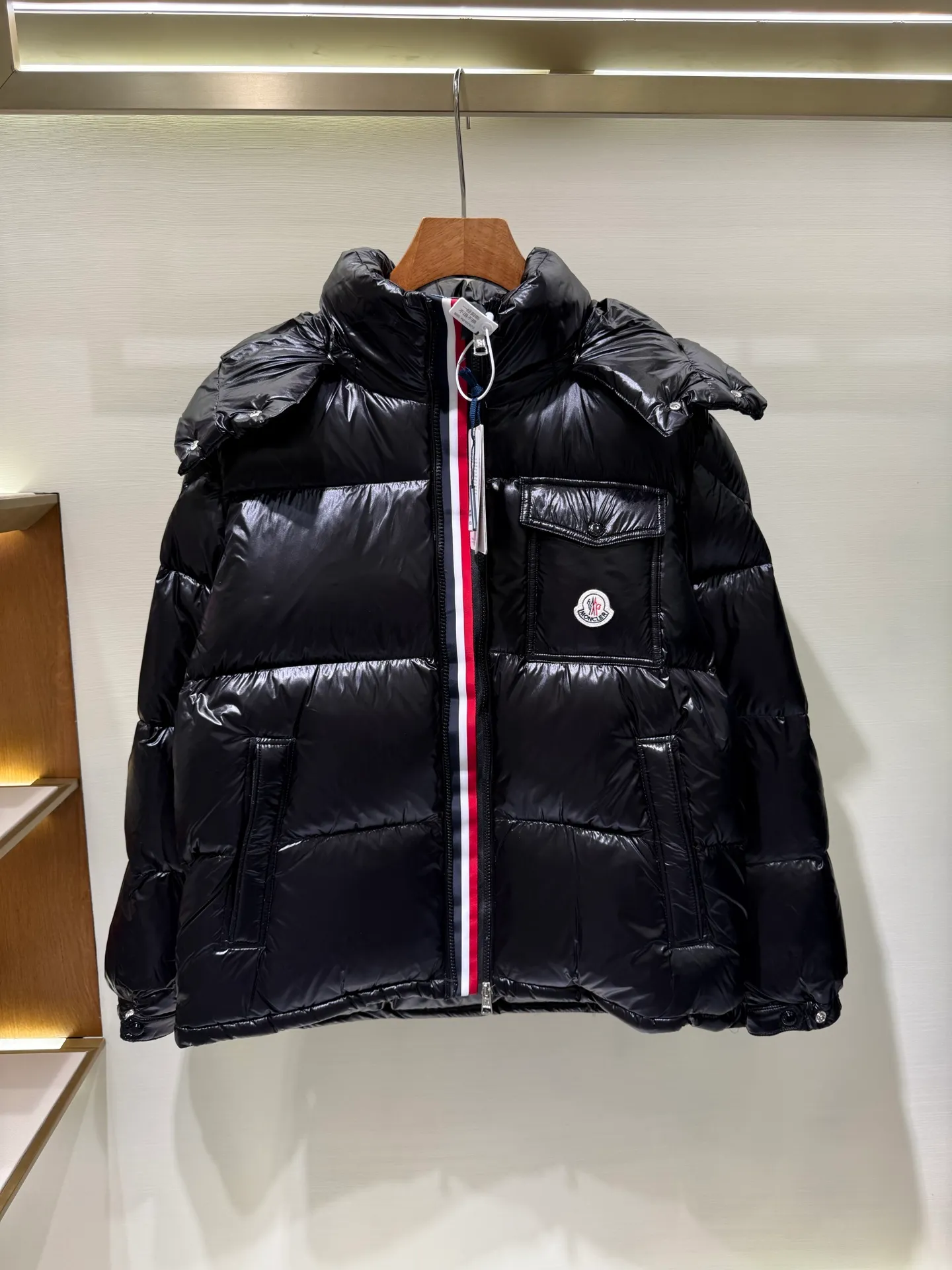 P1180 Moncler Montbeliard glossy down jacket The Montbeliard down jacket is made of shiny patent nylon and features highly recognizable rectangular quilting. Featuring a hooded design and signature patch pocket at chest.  Fabric: 100% nylon Filling content: 90% white goose down 250-300g Craftsmanship: Made of nylon laqué fabric Nylon laque lining Filled with down, detachable and adjustable hood with drawstring closure Built-in flap with webbing, black pocket details at the lower end Zipper closure Collar with snap buttons Zipper pockets Patch pockets with snap buttons Adjustable cuffs Adjustable elastic drawstring hem.  Size: 1 2 3 4 5 0548000