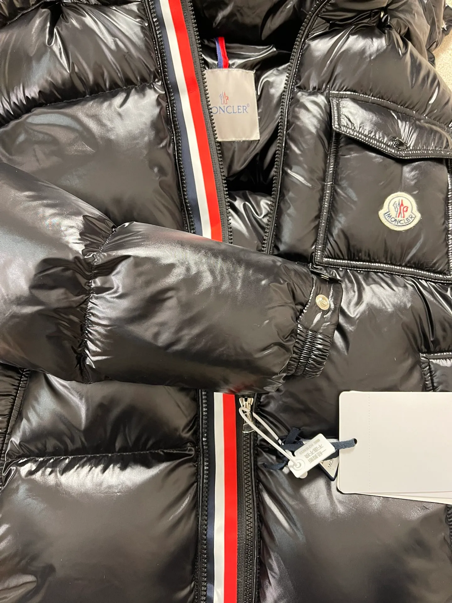 P1180 Moncler Montbeliard glossy down jacket The Montbeliard down jacket is made of shiny patent nylon and features highly recognizable rectangular quilting. Featuring a hooded design and signature patch pocket at chest.  Fabric: 100% nylon Filling content: 90% white goose down 250-300g Craftsmanship: Made of nylon laqué fabric Nylon laque lining Filled with down, detachable and adjustable hood with drawstring closure Built-in flap with webbing, black pocket details at the lower end Zipper closure Collar with snap buttons Zipper pockets Patch pockets with snap buttons Adjustable cuffs Adjustable elastic drawstring hem.  Size: 1 2 3 4 5 0548000
