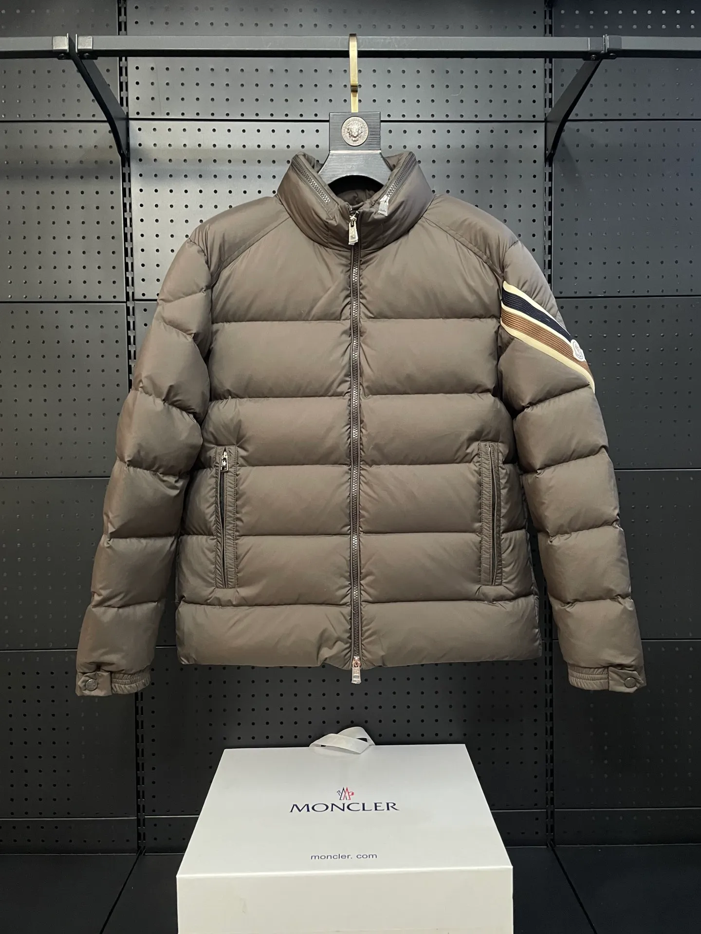 P840 🆕❤️2️⃣0️⃣2️⃣4️⃣🆕Premium down⬆️Moncler Solayan men's three-color trim short down jacket. Premium goose down filling. The finest, lightest and neatest fabric. Solayan men's short down jacket is decorated with seasonal iconic stripe details, blending sportsmanship and timeless style.  The Solayan down jacket is made of micro chic fabric and has a tough square shape design, highlighting Moncler's sporty spirit. This cropped down jacket features tricolor stripes on the sleeves, a seasonal take on the brand's signature. Comes with a practical pull-out hood. Details •Made from micro chic nylon fabric •Micro chic nylon lining •Down filled •Pull-out hood •Zip closure •Zip pockets •Adjustable cuffs •Elastic drawstring hem •Tri-color trim on sleeves Size: 1-5 Color: White Dark Brown Black