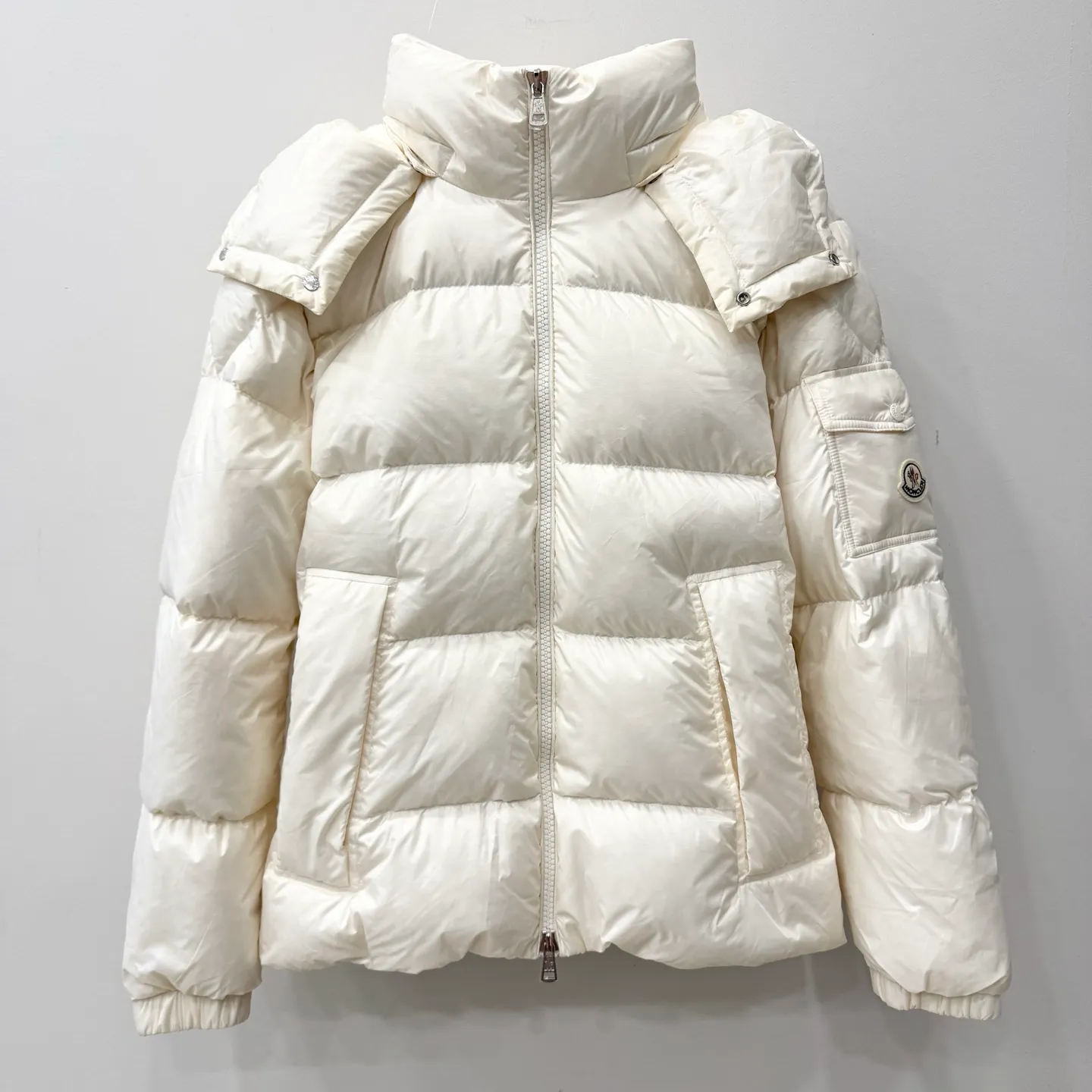P1100 Brand: Moncler Filling: 90 white duck down Weight: 380-450 Color: White Black Gray Size: 12345 [Couyere Men's Hooded Short Down Jacket] The Couyere short down jacket is durable and practical, provides functional warmth and care, and will accompany you to meet challenges.  The Couyere is a durable down jacket made from a fine fabric that's durable and functional, with velvet resistance and functionality. The short design creates a sculpted silhouette, and padded pockets add a modern feel. The sleeves are embellished with signature patch pockets, a nod to the classic Moncler Maya down jacket.  • Made of fine ripstop fabric • Fine fabric lining • Down filling • Detachable and adjustable hood • Zip closure • Zippered pockets • Press-studs on sleeve pockets • Elastic cuffs • Drawstring hem Fabric: 100% nylon; Lining: 100% nylon; Filling: Goose down Down content: 90%; except upholstery; Maximum wash temperature 30°C - Mild wash; Do not bleach; Do not tumble dry; Ironing maximum temperature 110°C - without steam; Hydrocarbon dry cleaning - gentle wash; Professional wet cleaning - gentle wash; Lay flat to dry in shade; Wash separately; Remove removable accessories before washing; Recommend washing and ironing inside out