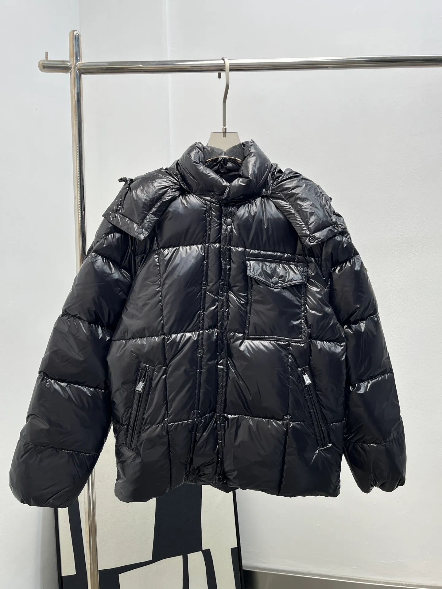 P1160 Moncler 25 new serfanto hooded buttoned down jacket for men and women. This hooded warm piece is equipped with double snap button closure to create an asymmetrical shape. Trimmed with quilting in varying sizes for a geometric feel