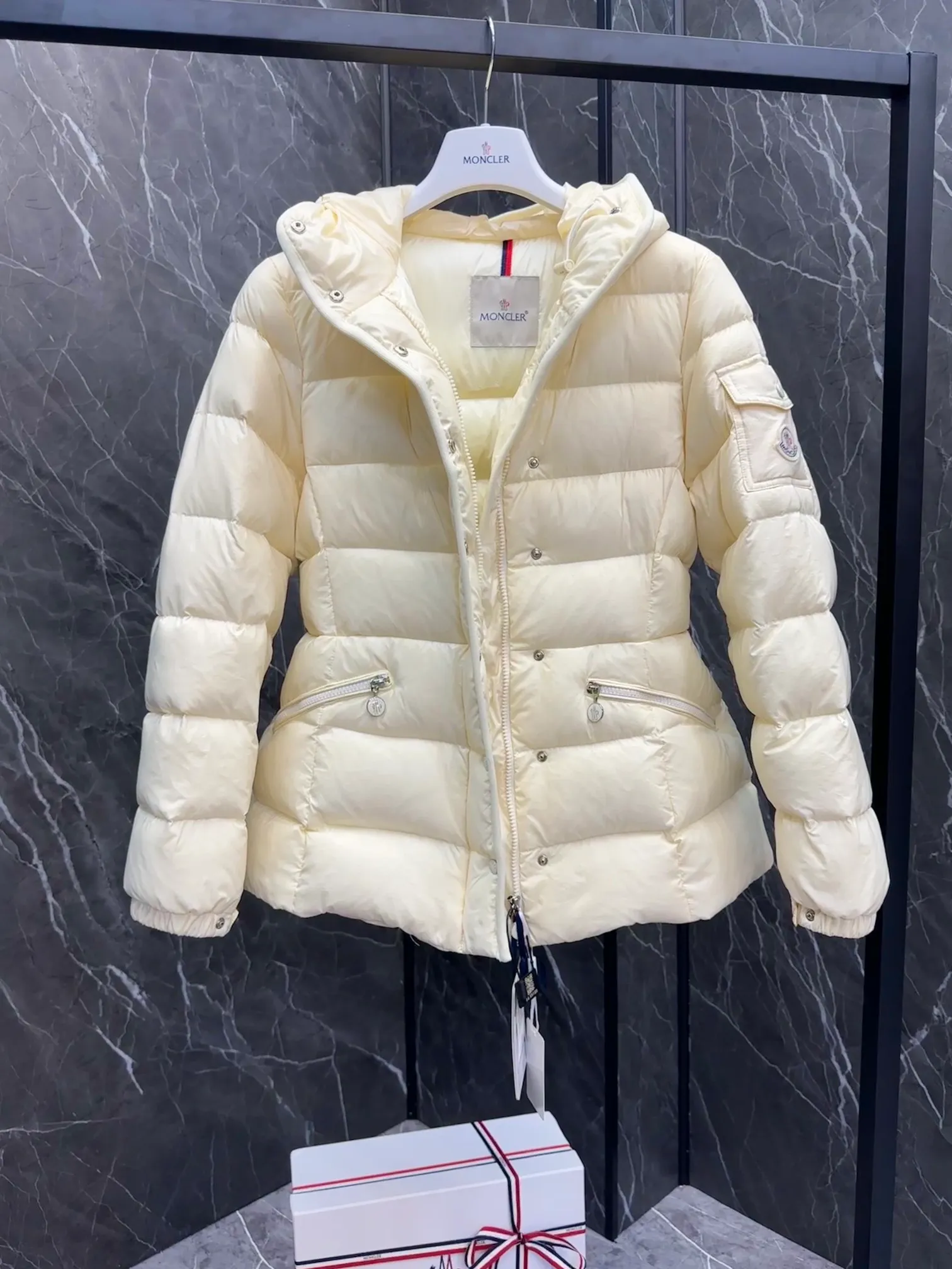 P780 Hot Sale ⬆️Moncler Barante Women’s Short Down Jacket The Barante short down jacket combines femininity with practical functions, reinterpreting the aesthetic style of the 1970s for modern women. The Barante down jacket is made from lustrous nylon and is inspired by the 1970s. It adopts a waist design and presents an A-line silhouette, highlighting a feminine style. An adjustable hood and signature logo patch add finishing touches. Details •Made of nylon laqué fabric •Nylon laqué lining •Down filling •Adjustable hood •Zip and snap closure •Suit pocket •Adjustable cuffs Size : 0-3. Snow White/Light Pink/Black.
