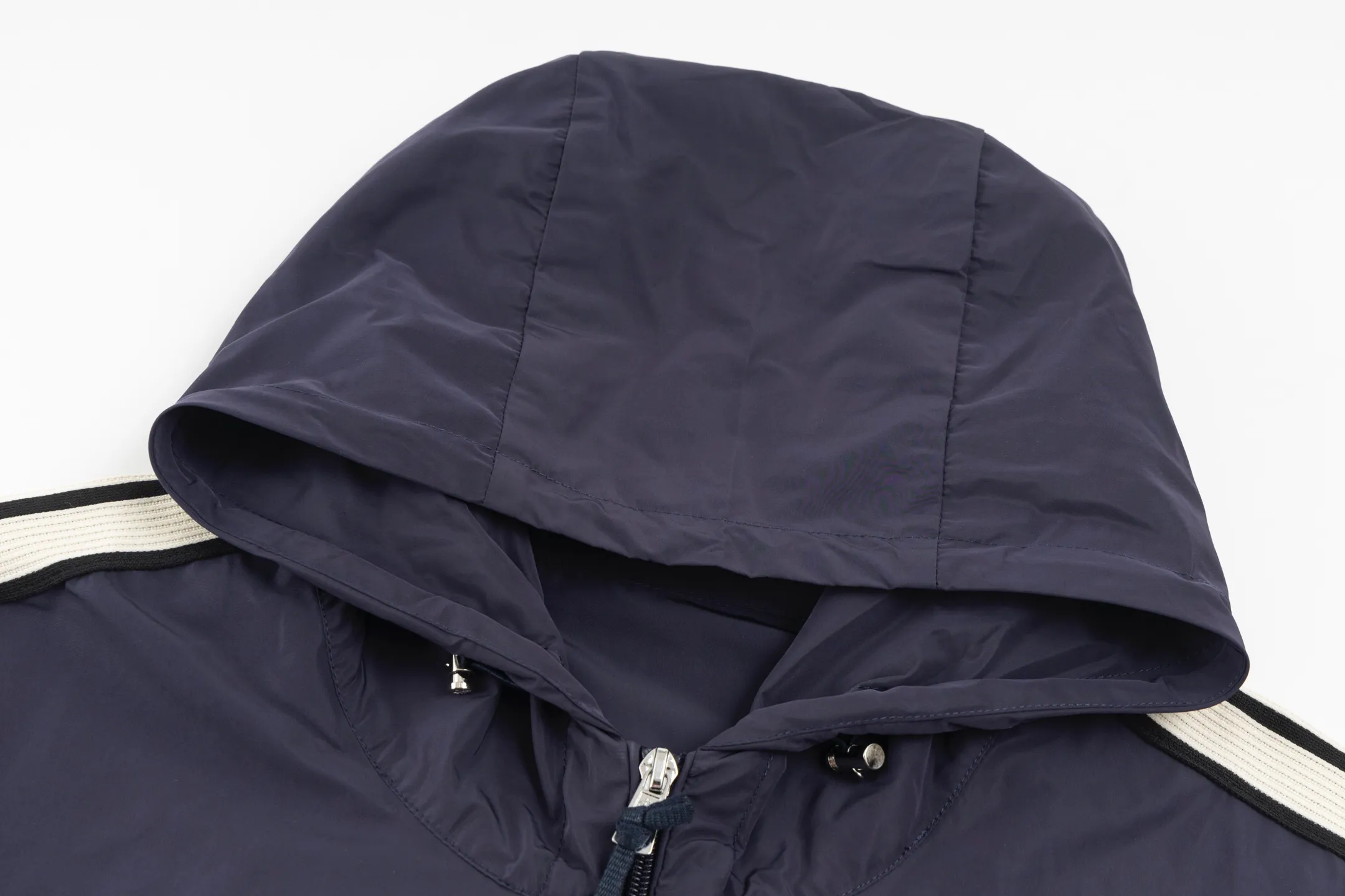 P550 Exclusive supply] Moncler Webbing Armband Lightweight Jacket (Navy Blue) The fabric is made of 100% polyester fiber to create a tough protective outer layer. It is known for its excellent tear resistance and wear resistance. It can quickly return to flatness during wearing and maintain the crisp and stylish appearance of the clothing for a long time. At the same time, it is not easy to deform after being washed for a long time. Decorative edging in two different colors has been added to the center section of the sleeves. This design element not only adds visual highlights to the clothing, making it more fashionable and unique, the webbing is precisely positioned along the specified contours from the cuffs to the seam of the collar to ensure symmetry and overall smoothness. Before actual sewing, use very fine basting stitches for pre-fixing. This step is crucial to prevent the webbing from slipping, twisting, or wrinkling during sewing and ensuring that the final stitch is straight and perfect. Size:1/2/3/4