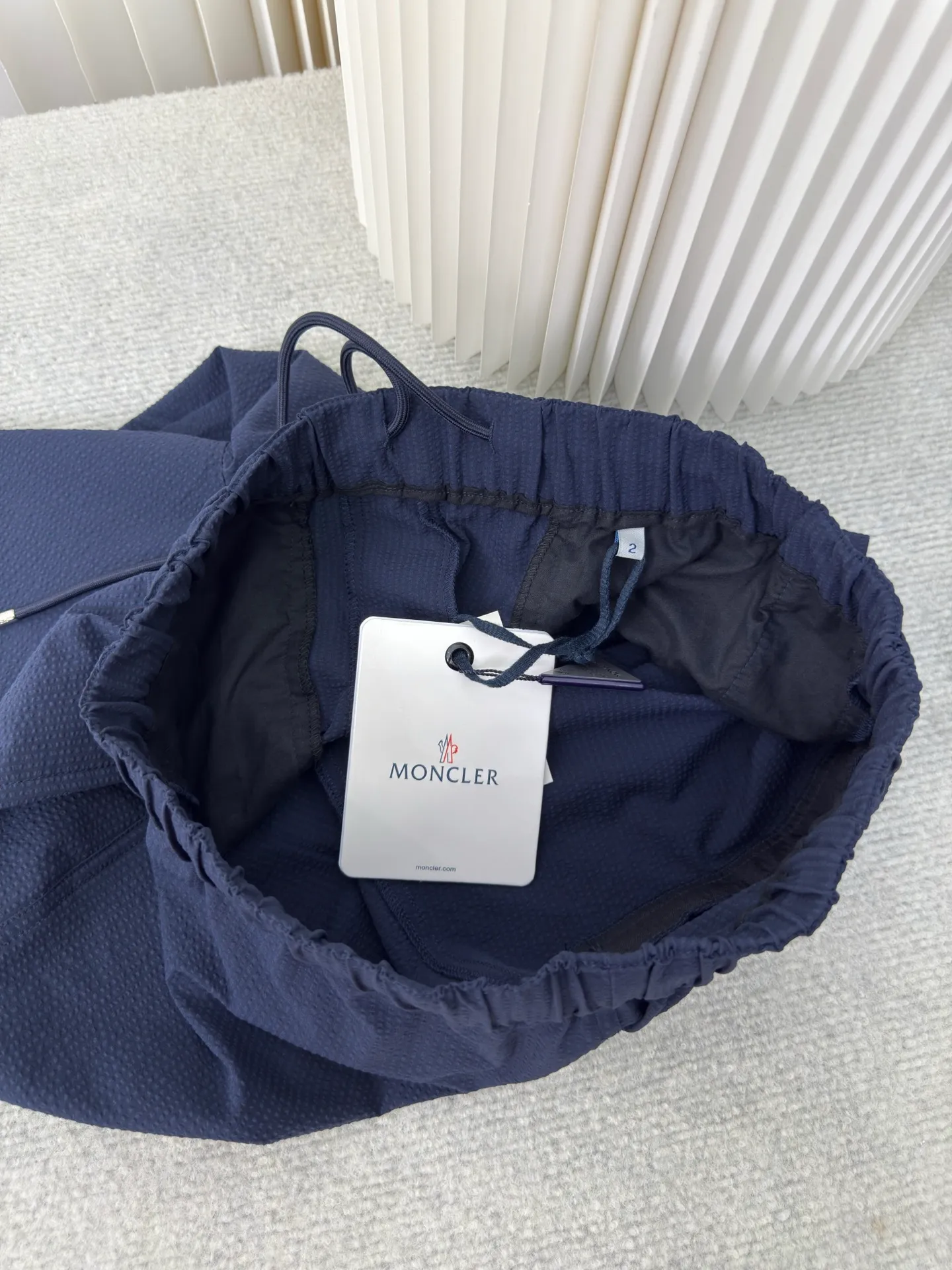 P410 MONCLER Puff Wrinkle Pants with Mouth, Authentic Open Version - Physical Counter - Top Luxury Quality 🆚Second Price of All Versions on the Market Made of cotton blended woven fabric with 76% high cotton content + 24% polyester fiber. The high cotton content ensures that the fabric is soft, skin-friendly, and has good breathability. The addition of a small amount of polyester fiber balances the wrinkle resistance and elasticity of the overall fabric and greatly reduces its shrinkage. After preshrinking, dimensional changes during washing are negligible. The fusion of the two makes the fabric combine anti-wrinkle, quick-drying, easy care and other characteristics without losing the advantages of good wearing experience and strong breathability.  The ground warp + bubble warp is independently let-off. The bubble warp yarn feeding speed is about 20% higher than the ground warp yarn feeding speed. During weaving, the bubble warp is relaxed and accumulated, forming a naturally arched bubble unit. Through the alternating arrangement of yarns and the change of floating tissue, a clear grid frame is built between the bubble units. Finally, the bubble three-dimensional effect and grid outline are locked through high-temperature heat setting. Size:1 2 3 4