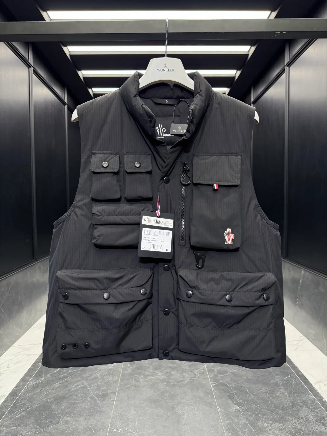 P820 ​​Premium Down ⬆️Moncler Grenoble Tongass Down Outdoor Vest. High-end Black Label Series. Original replacement fabric. Premium duck neck down filling. The Tongass Down Vest provides protection without being heavy and is specially designed for outdoor activities in mild weather.  The Tongass down vest is the result of research into lightweight performance outerwear. Functional fabric is tight and durable without adding extra weight. Features a large utility pocket and carabiner clip to reduce the amount of luggage you carry. Details •Designed for outdoor activities •Made from tight fabric •Polyester lining •Down filling •Snap button closure •Utility pockets with snap, zip and Velcro closure •Drawstring hem •Front carabiner •Reflective details Size: 1-5 Light Brown/Black D00780