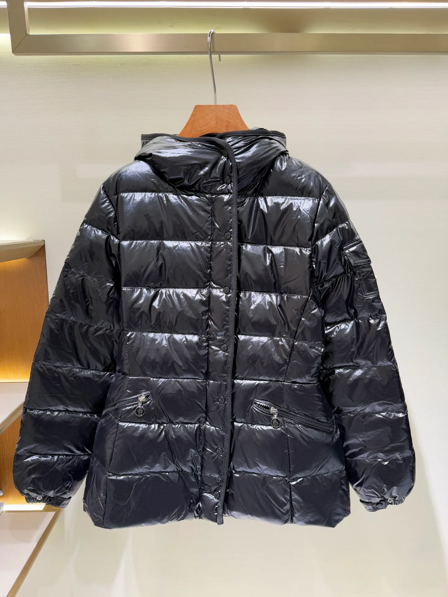 P1140 Moncler Barante series short waisted down jacket. The Barante down jacket is made of glossy nylon fabric and is inspired by the 1970s. The short version features a nipped-in waist and an A-line silhouette, highlighting a feminine style. An adjustable hood and signature logo patch add finishing touches.  Fabric: Made of nylon laque fabric, Nylon laque lining, filled with down (90 white goose down) Craftsmanship: Adjustable hood, zipper and snap button closure, zipper pocket Adjustable cuffs (supports NFC function) Color: black pink off-white Size: 0 1 2 3 4446080