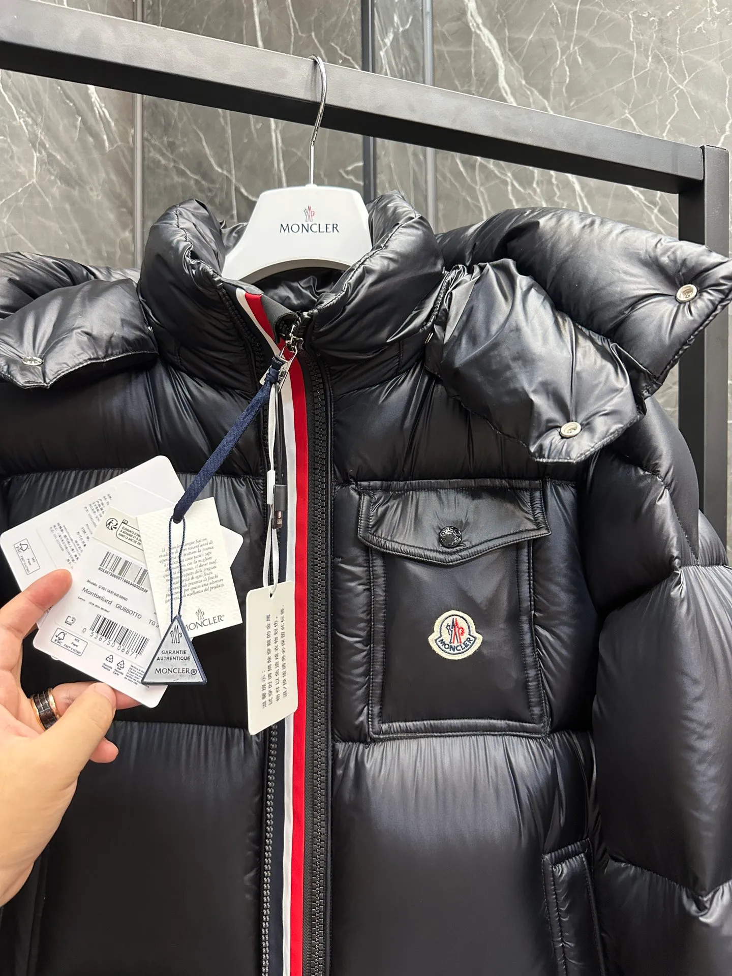P740 ⬆️Moncler Montbeliard Short Men's Down Jacket Jacket Montbeliard Men's Short Down Jacket has warmth and protection functions, highlighting the fashionable Moncler aesthetic, and is a popular product. The Montbeliard down jacket is made from shiny patented nylon and features recognizable rectangular quilting. Featuring a hooded design and signature patch pocket at chest. Details •Made from nylon laqué fabric •Nylon laqué lining •Filled with down •Removable and adjustable hood with drawstring closure •Internal flap with webbing •Black pocket detail at lower end •Zipper closure •Snap-button closure at collar •Zipper pockets •Push-button closure at patch pockets •Adjustable cuffs •Adjustable elastic drawstring hem Size: 1-5 Couple's Black D9875067650